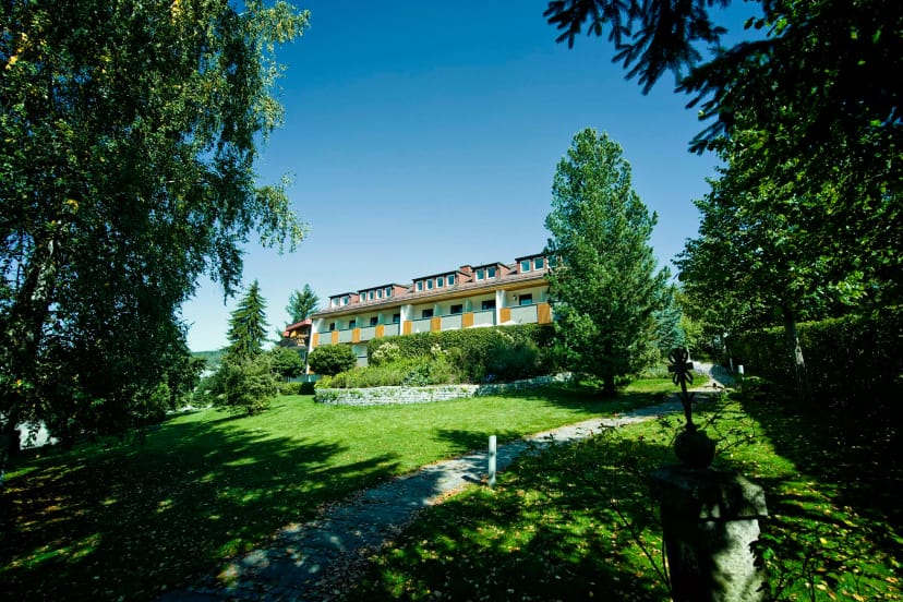 Außenansicht des Hotels mit weitläufigem Garten unter blauem Himmel