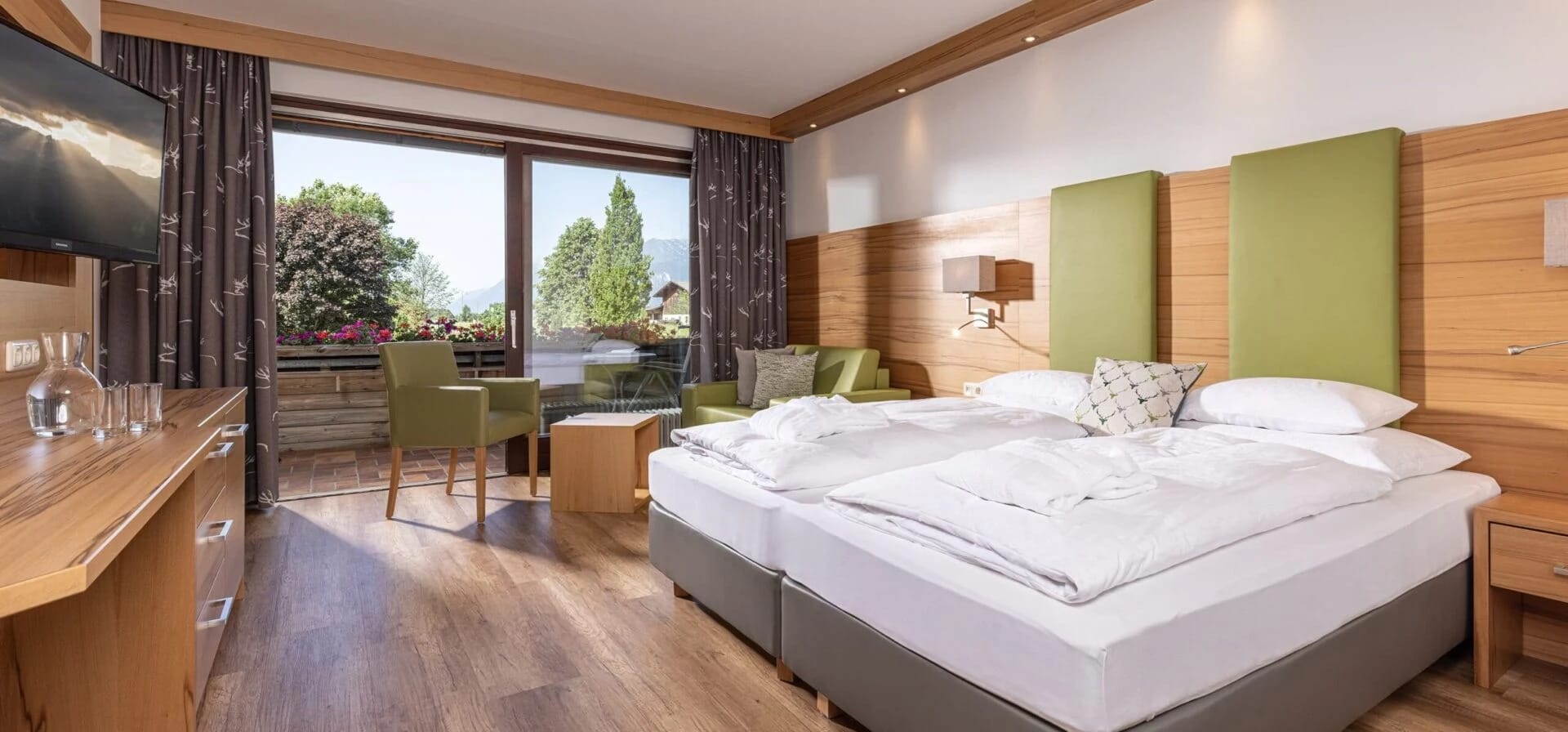 Helles Doppelzimmer mit Holzfurnier, grünen Akzenten, Balkonzugang und Bergblick