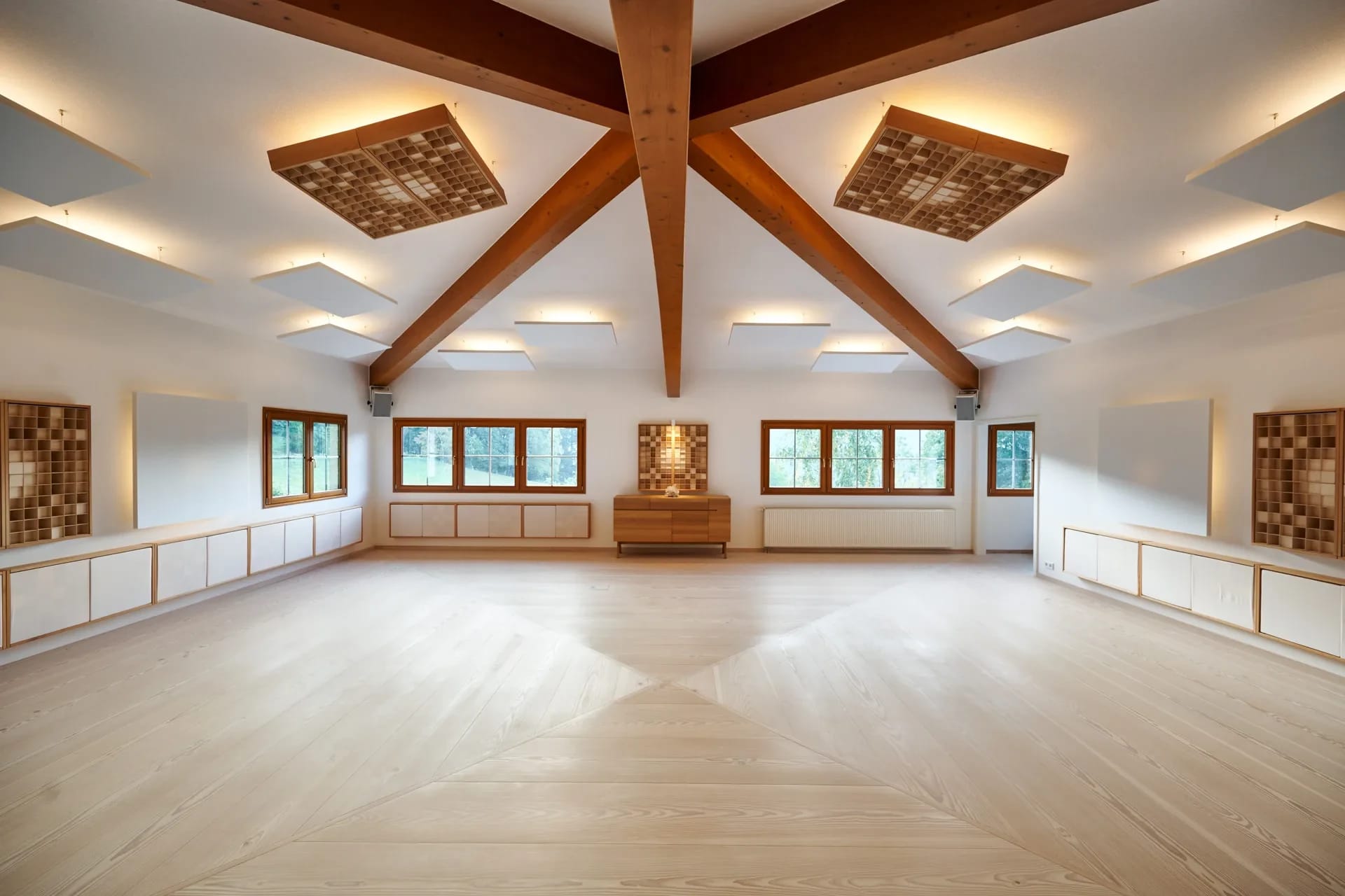 Großer heller Seminarraum mit hellem Holzboden, sichtbaren Holzbalken und Akustikelementen an der Decke
