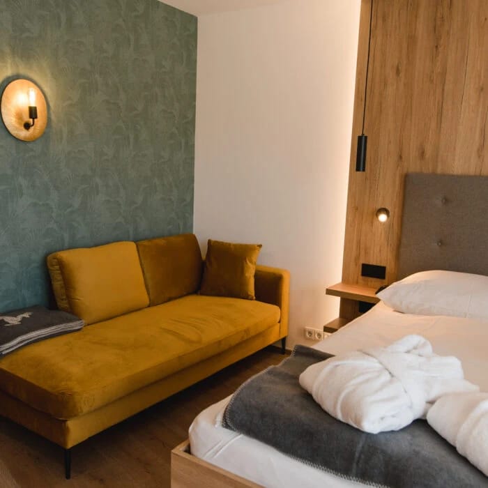 Zimmer mit grünem Sofa und Balkonzugang
