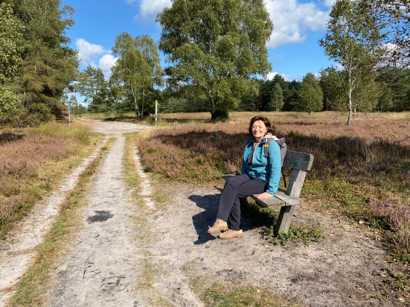 Porträt von Antje Schmidt auf einer Bank in der Heidelandschaft