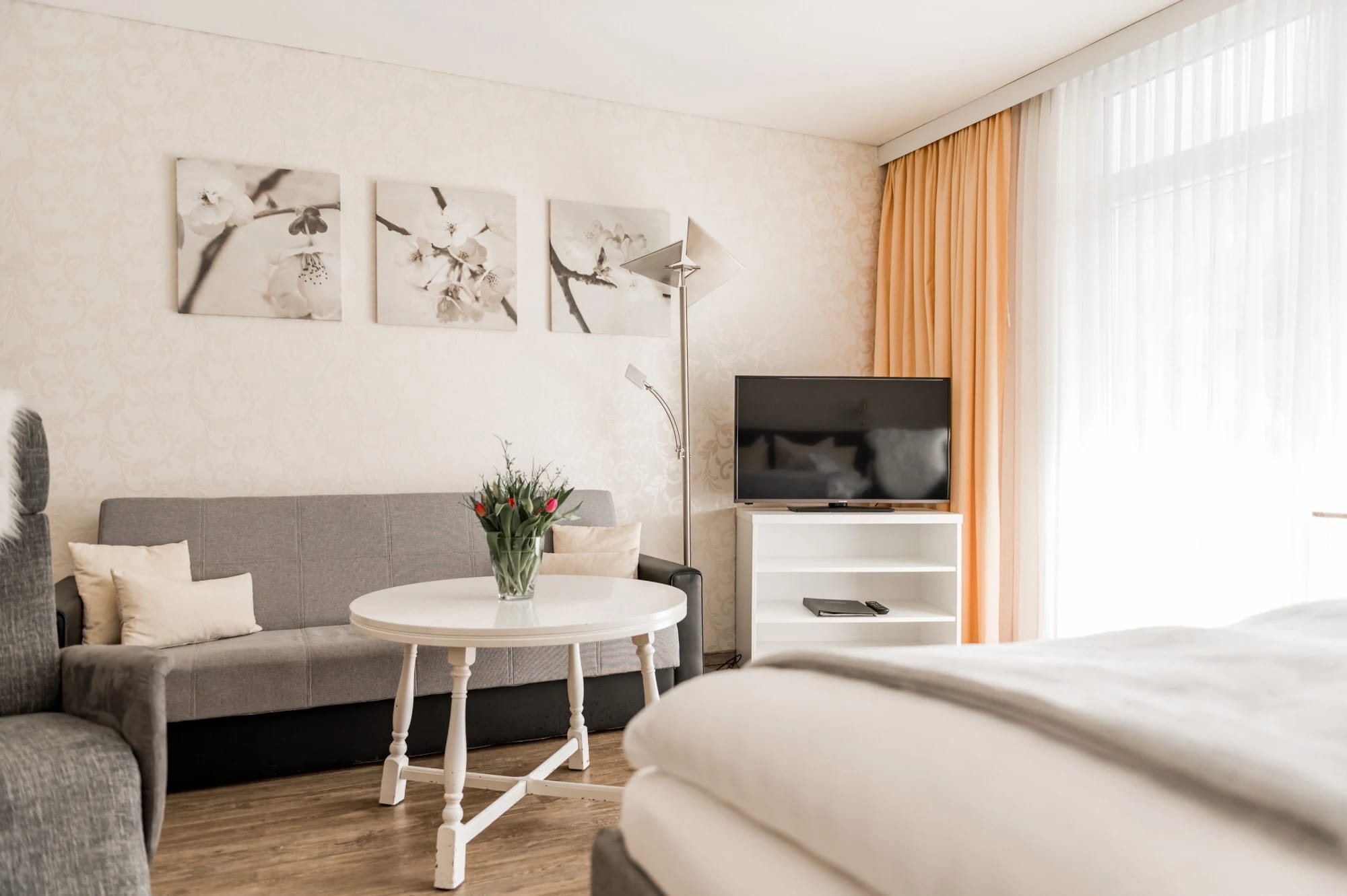 Sitzbereich im Zimmer mit grauem Sofa, weißem Couchtisch und Fernseher