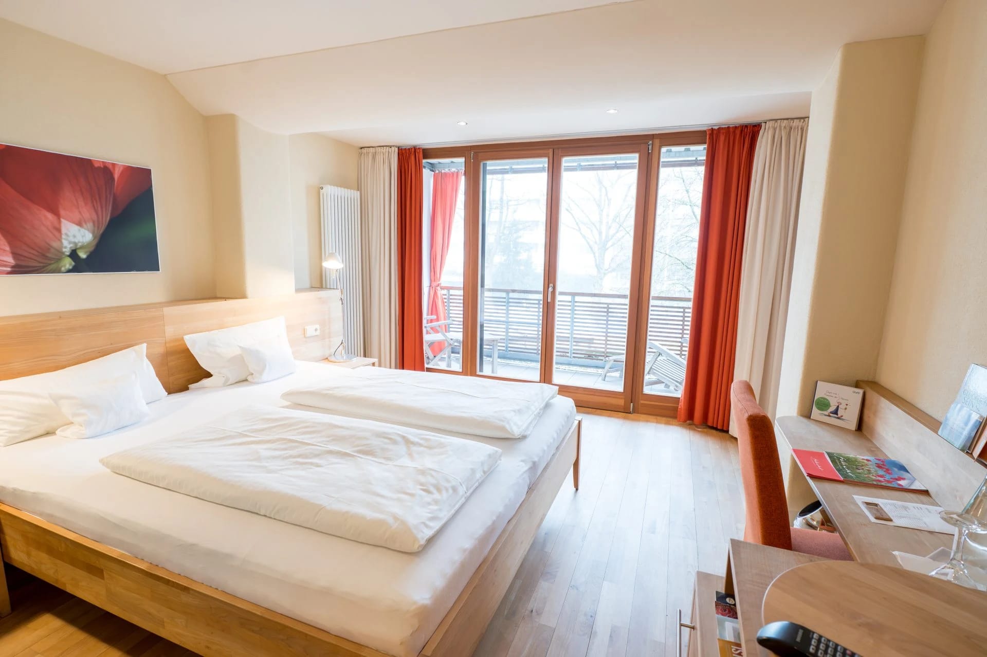 Doppelzimmer mit Doppelbett, bodentiefer Balkontür und Schreibtisch