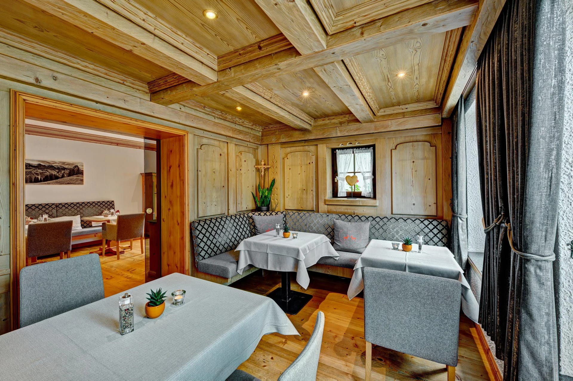 Gaststube mit Holzvertäfelung, Kassettendecke, eingedeckten Tischen und Eckbank