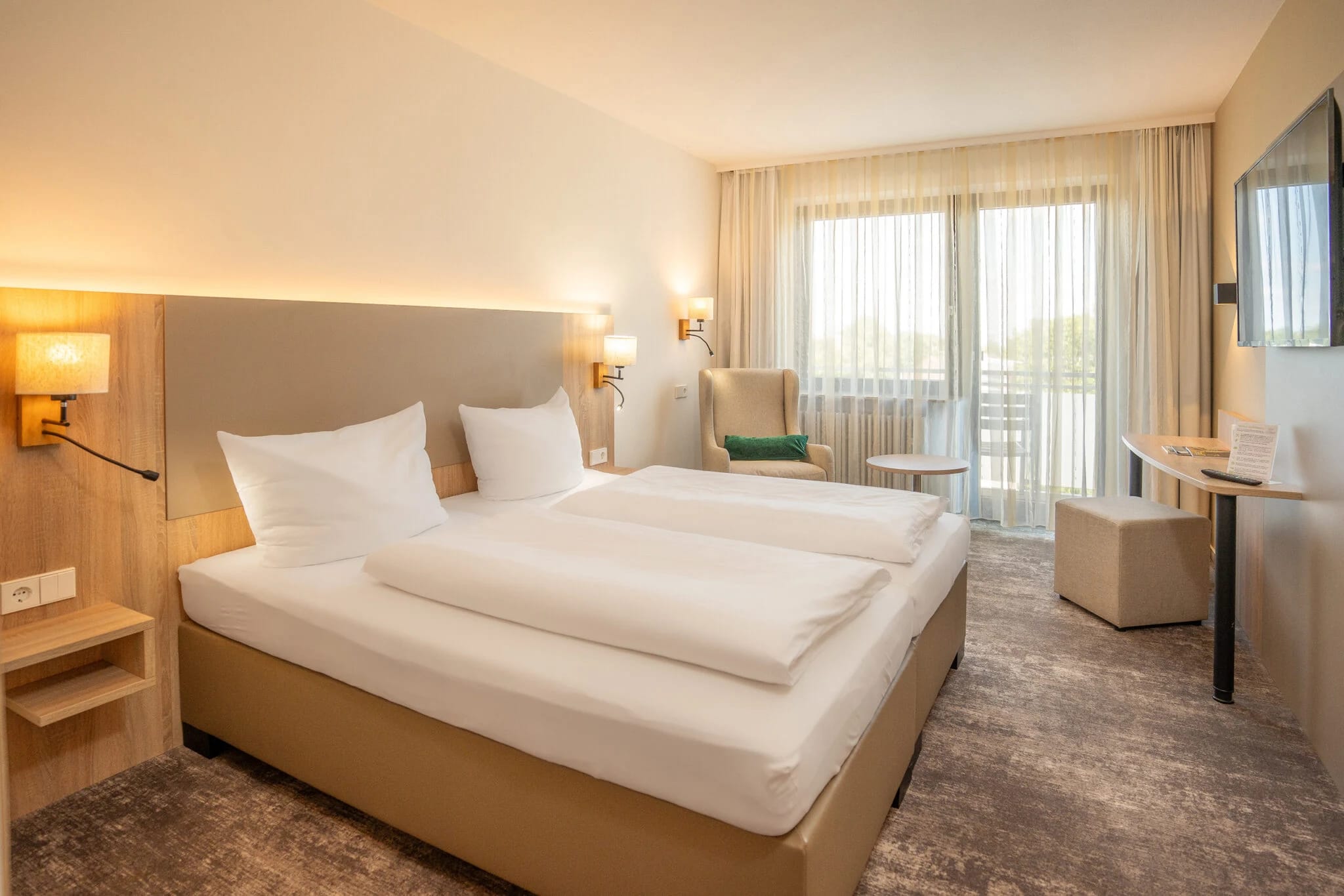 Doppelzimmer mit Doppelbett, Sessel und Balkontür