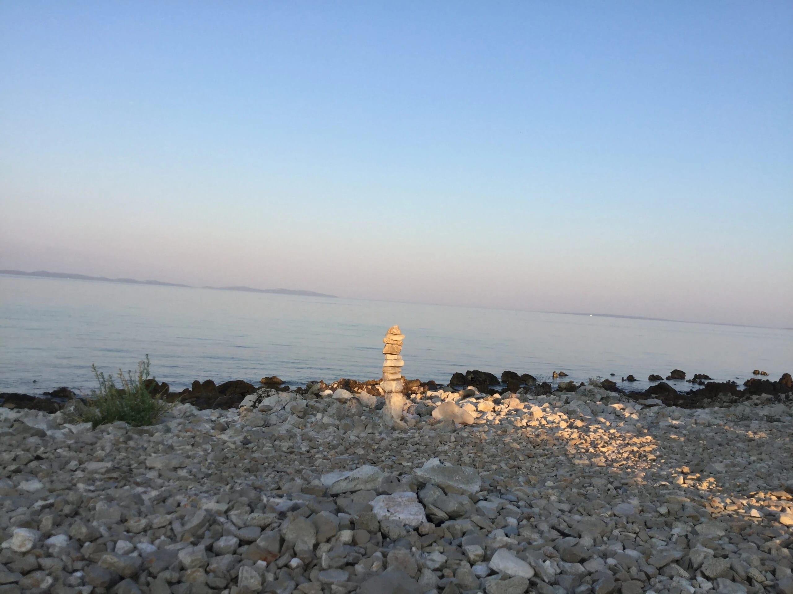 Steinmännchen an einem Kieselstrand bei Abendlicht