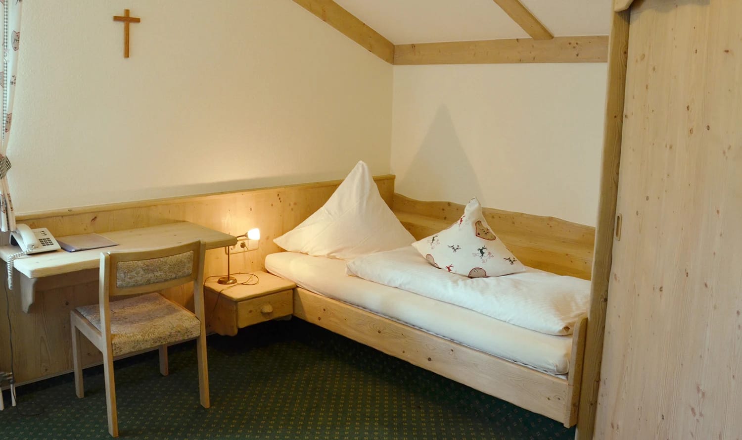 Einzelzimmer mit Bett, Schreibtisch und Holzelementen