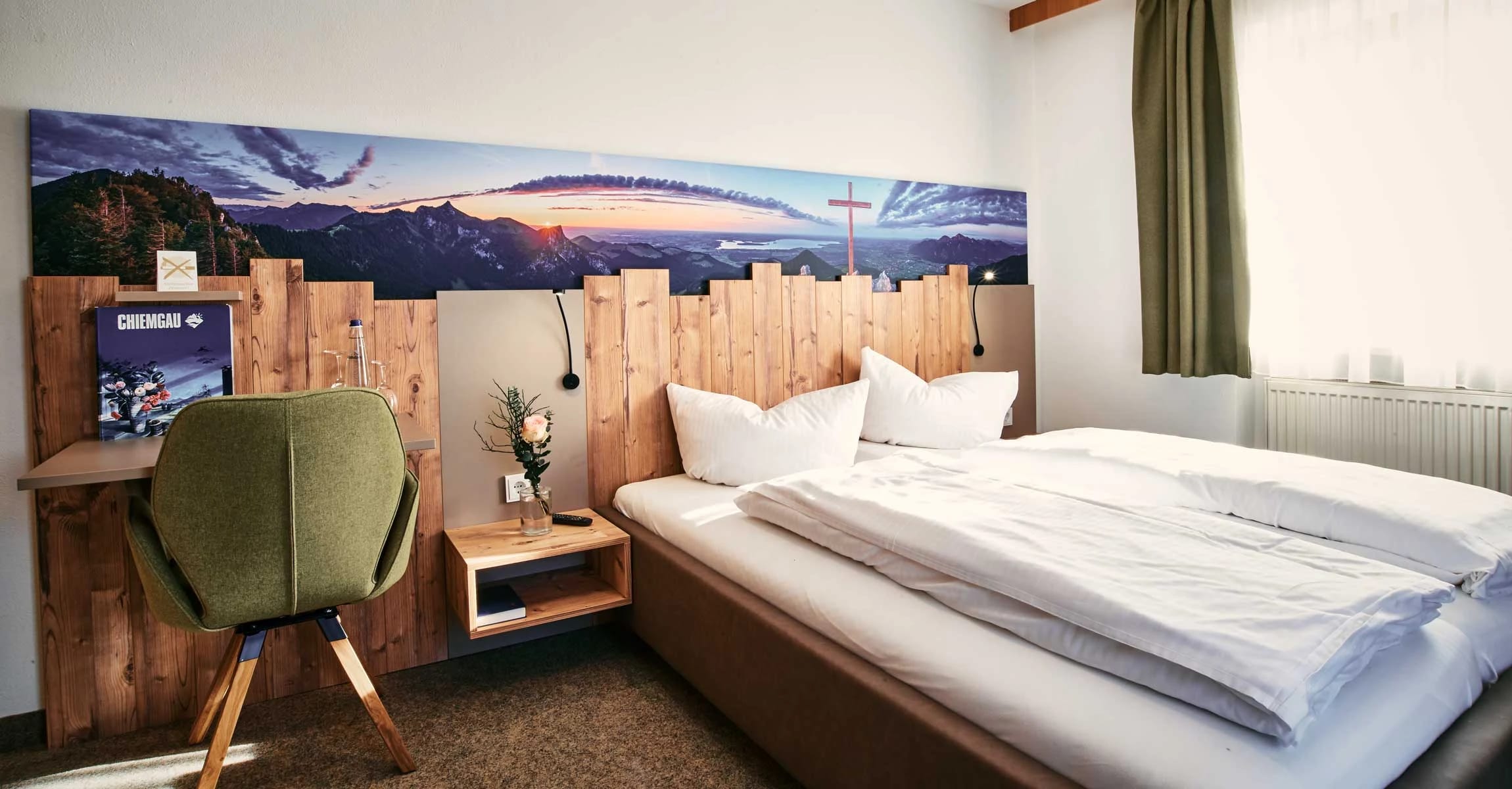Zimmer mit Holzverkleidung am Bettkopfende, Bergpanorama-Bild, Schreibtisch und grünem Sessel