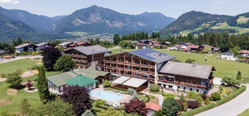 Luftaufnahme des Hotel Pirchnerhof im Sommer mit Außenpool, Gartenanlage und Tiroler Bergpanorama