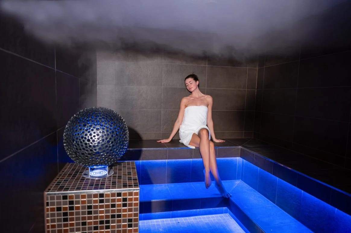 Dampfbad mit blauer Beleuchtung und gefliesten Sitzstufen