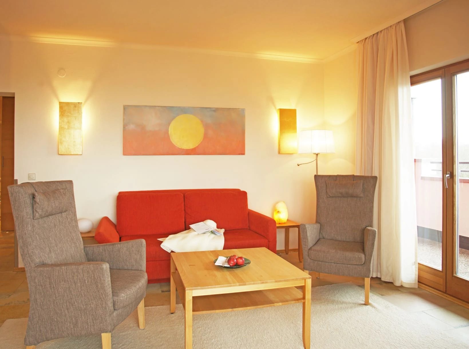 Wohnbereich einer Suite mit rotem Sofa und zwei Sesseln