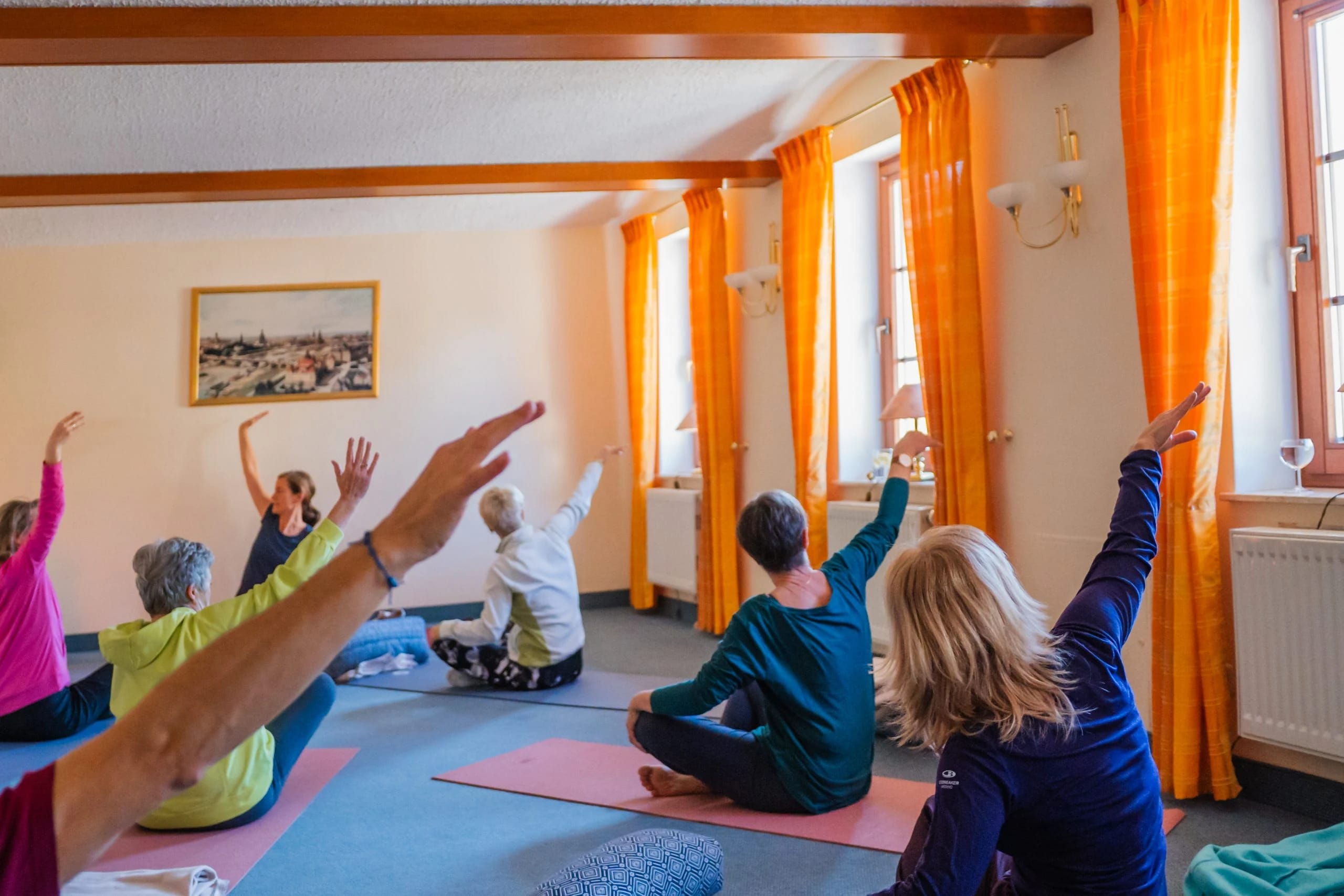 Yogagruppe mit erhobenen Armen in einem Seminarraum