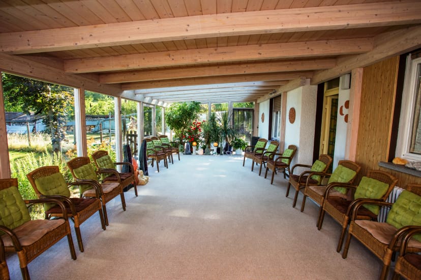 Überdachte Terrasse mit Holzdecke, Korbsesseln und Blick in den Garten