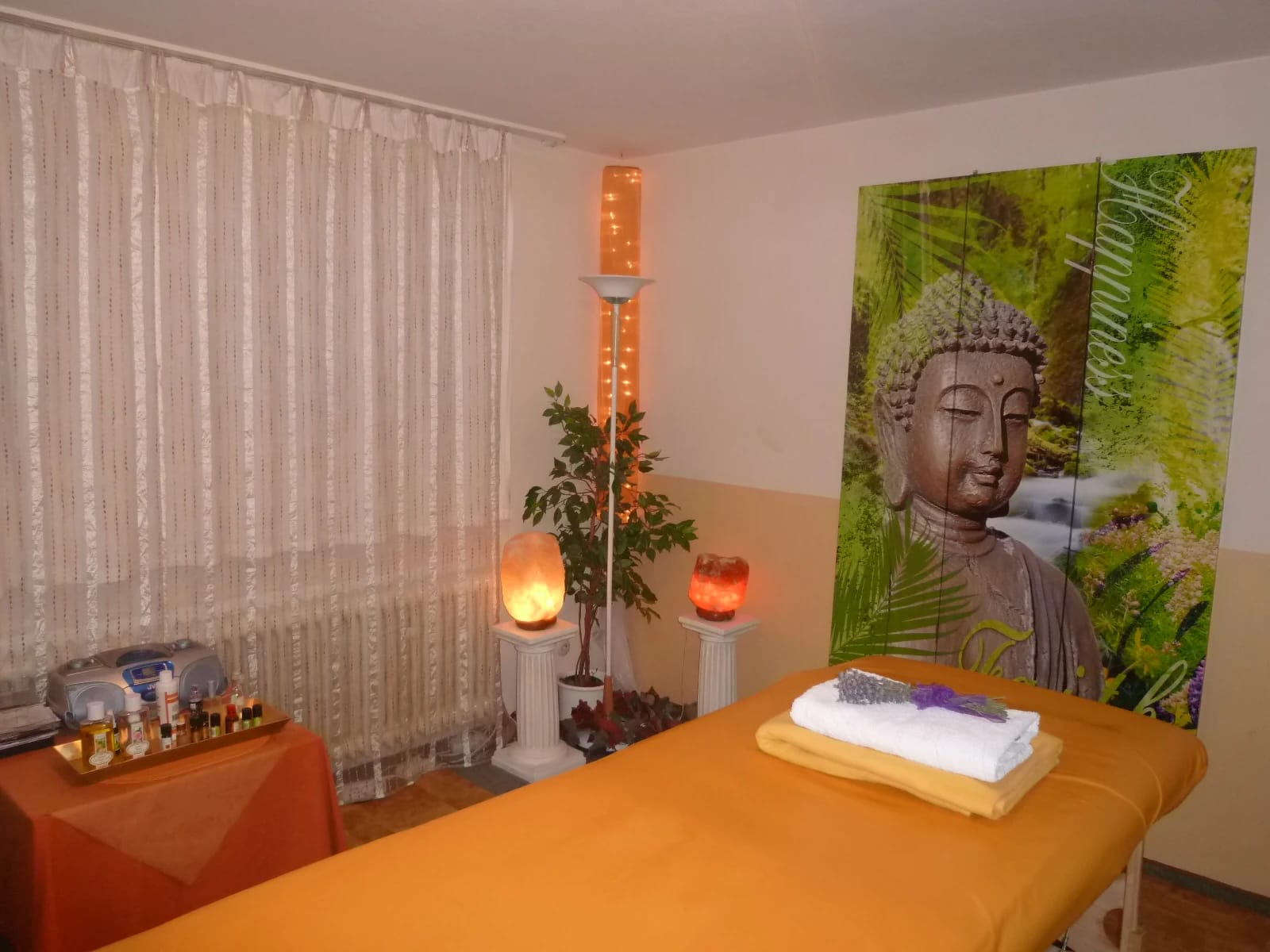 Massageraum mit Behandlungsliege, Salzlampen und Wandbild