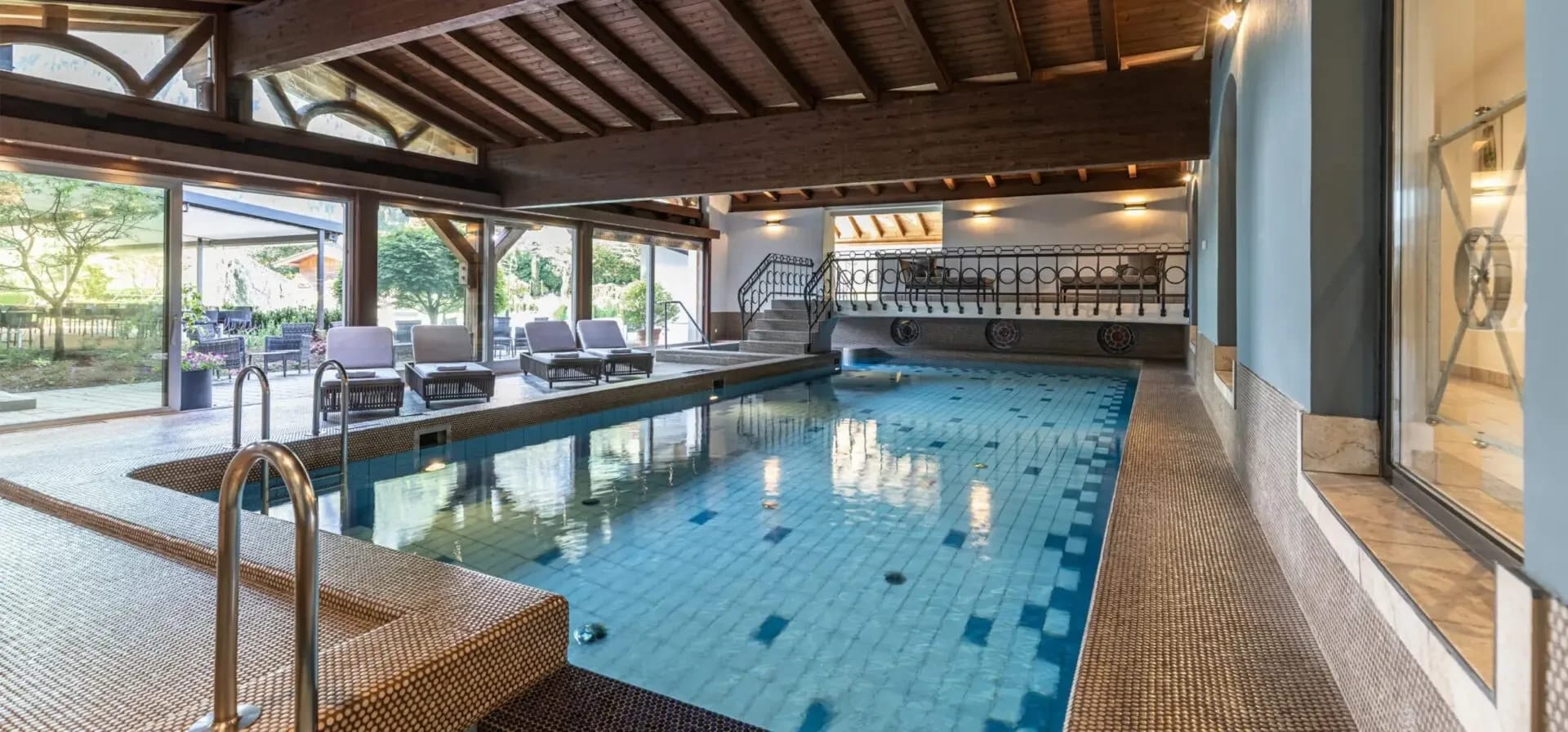 Hallenbad des Hotel Pirchnerhof mit großen Panoramafenstern und Liegestühlen