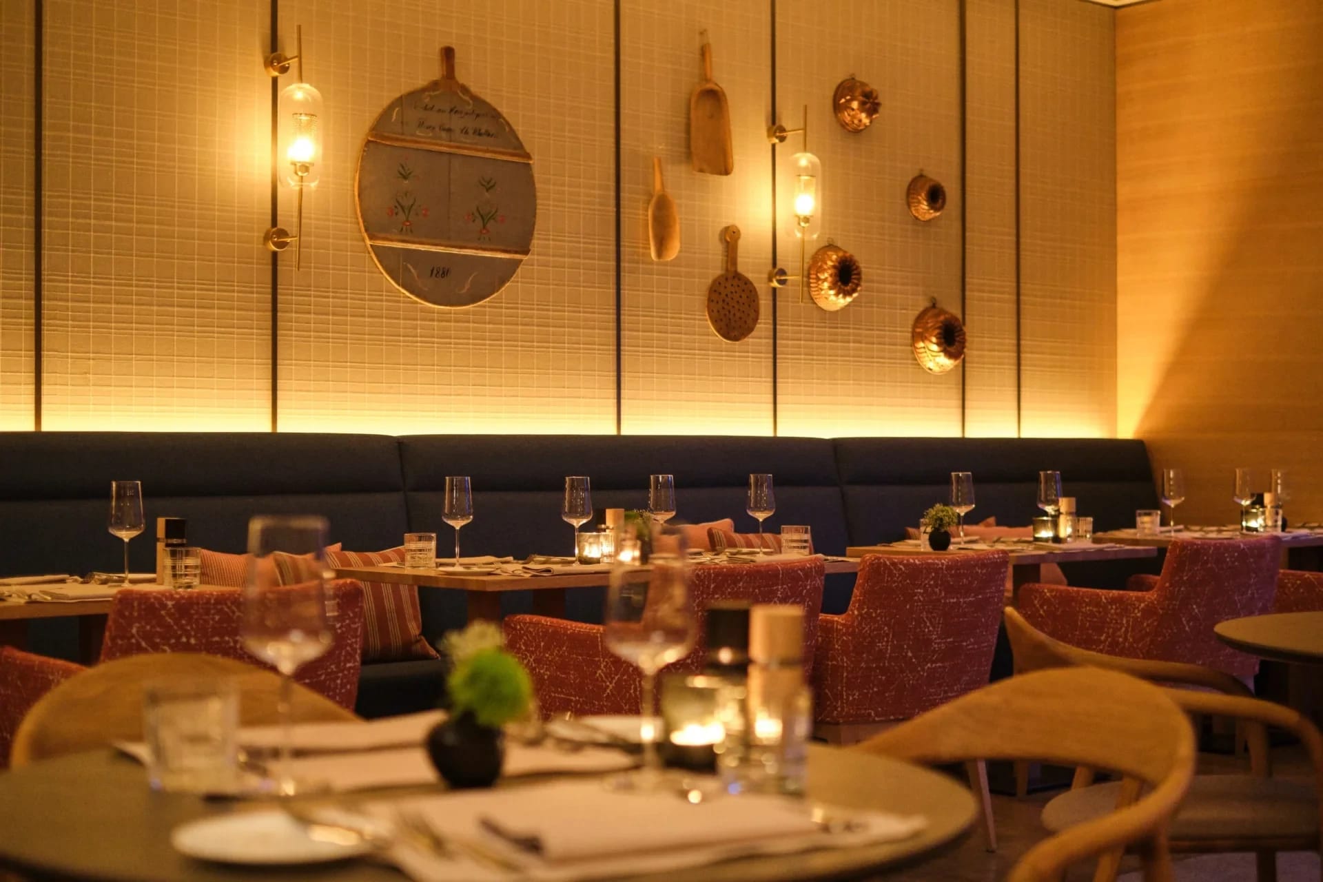 Restaurantraum mit eingedeckten Tischen, Bankbestuhlung und warmem Hängeleuchtenlicht