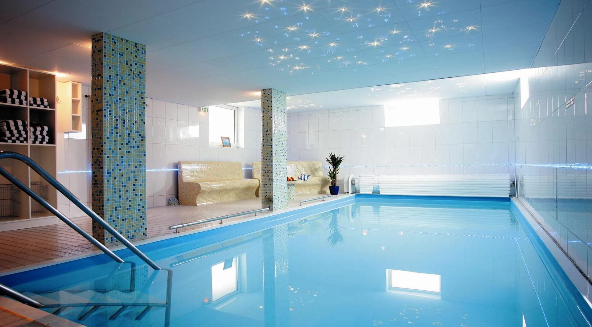 Hallenbad mit blauem Becken, Mosaiksäulen und Sternenhimmel-Decke