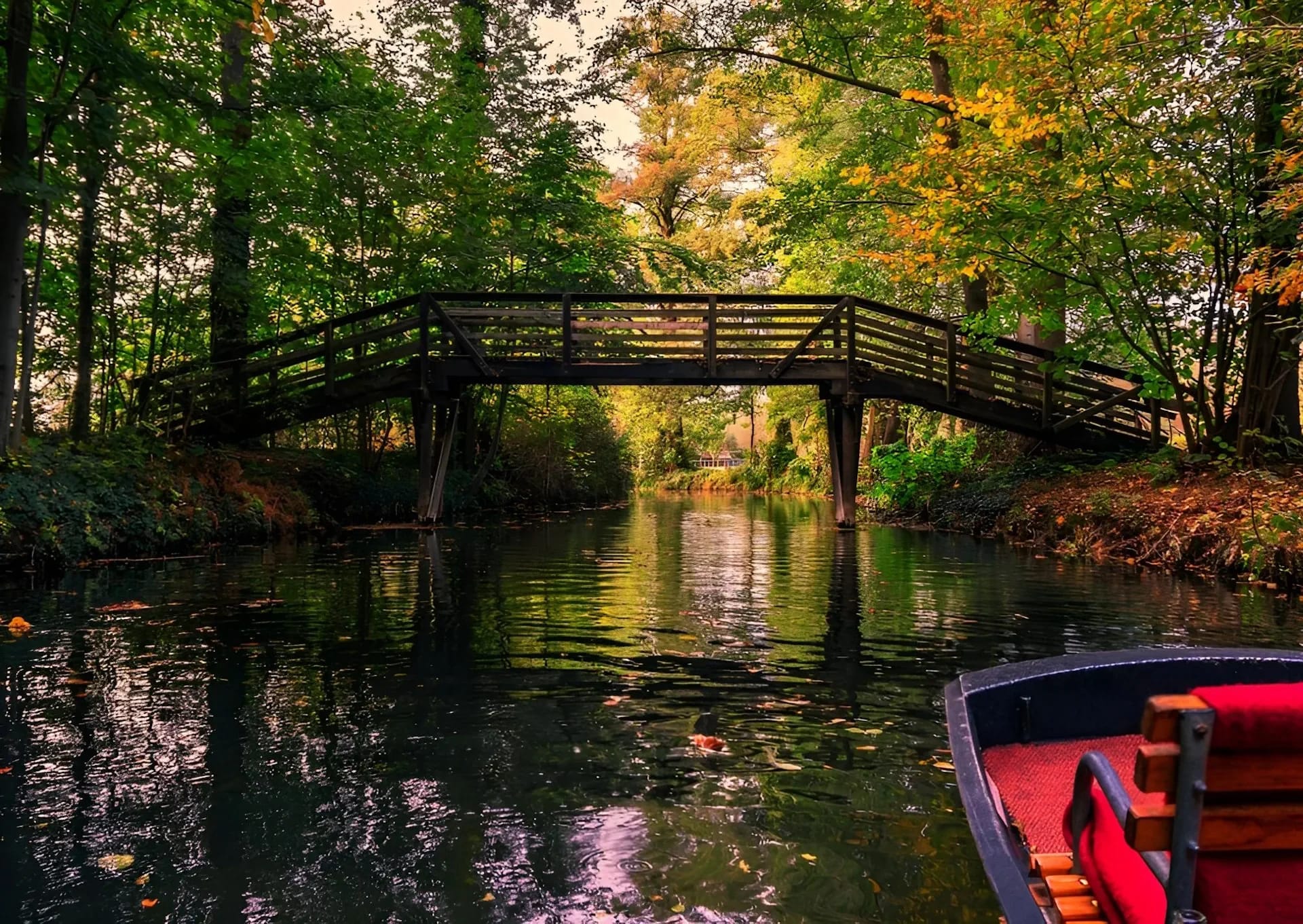 Spreewaldfließ mit Holzbrücke im Herbst, im Vordergrund der Bug eines Kahns