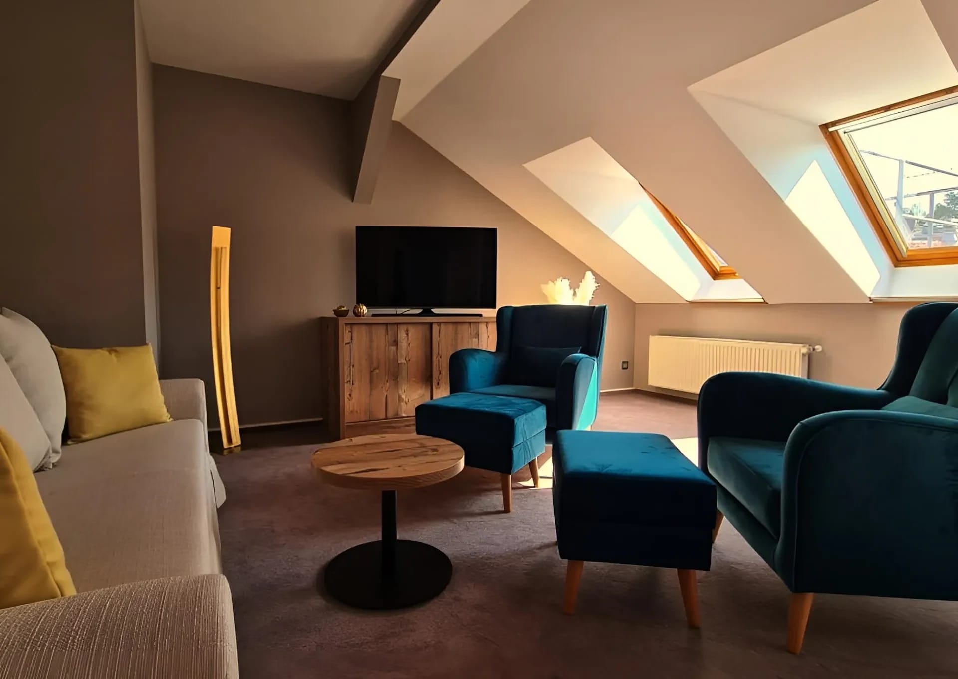 Wohnbereich unter der Dachschräge mit Sofa, Sesseln und Fernseher