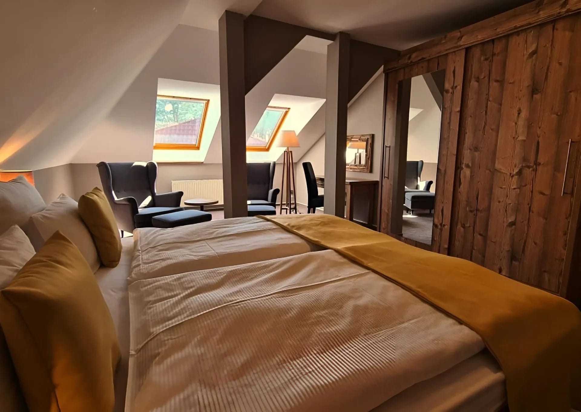 Dachgeschosszimmer mit Holzbalken, Doppelbett und Dachfenstern