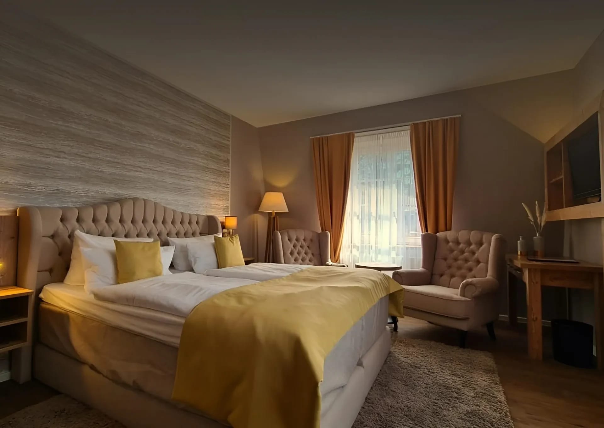 Doppelzimmer mit gepolstertem Bettkopfteil, zwei Sesseln und Fenster