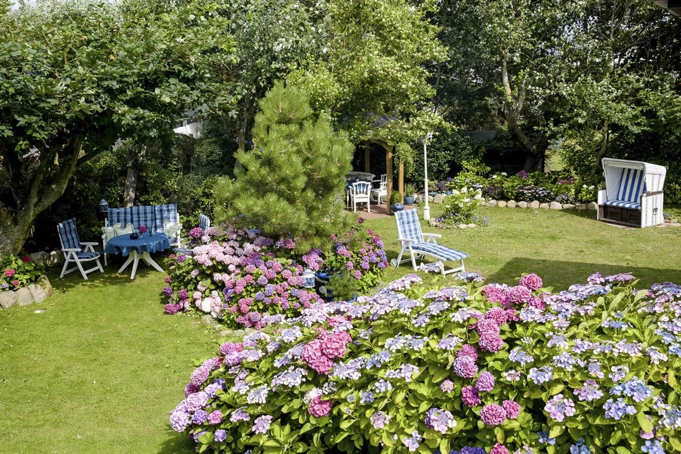 Gepflegter Garten mit Hortensien, Sitzplätzen und Strandkorb