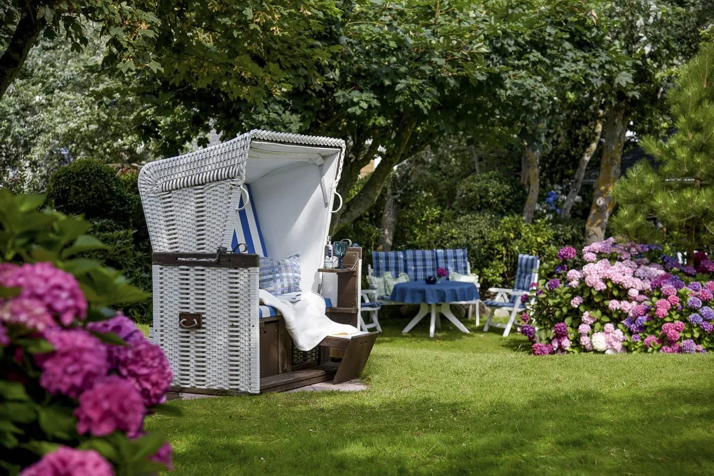 Weißer Strandkorb im blühenden Hortensiengarten