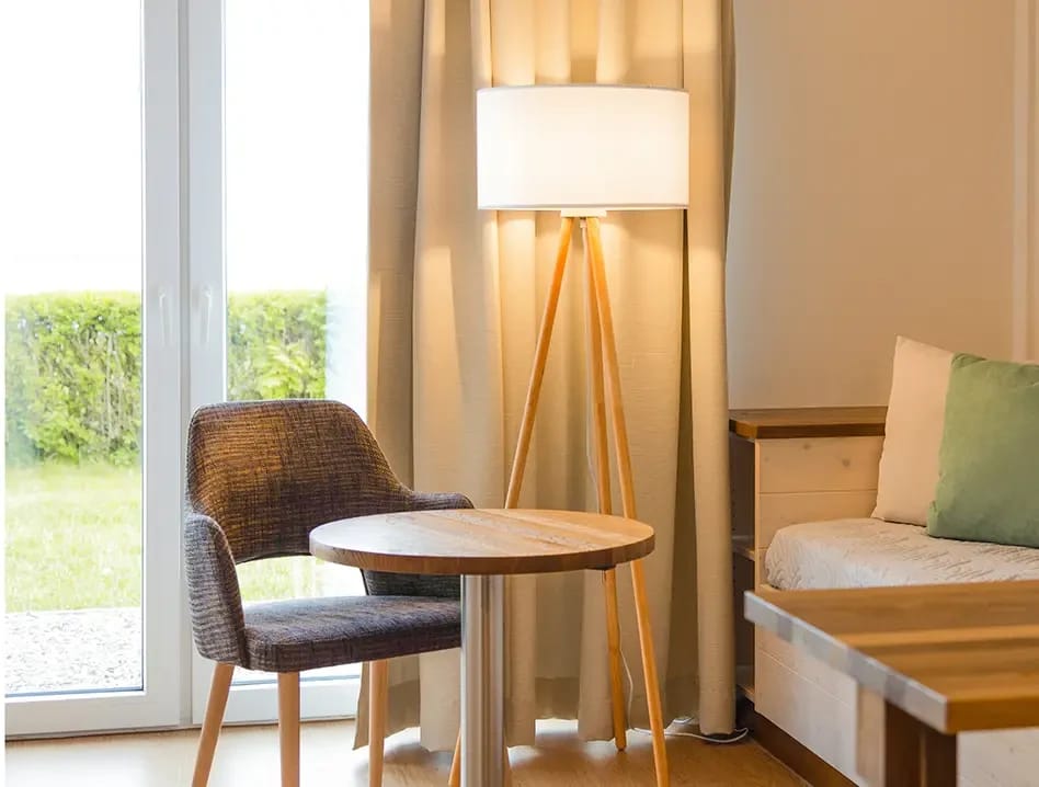 Sitzecke im Zimmer mit Sessel, Stehlampe und Holztisch am Fenster