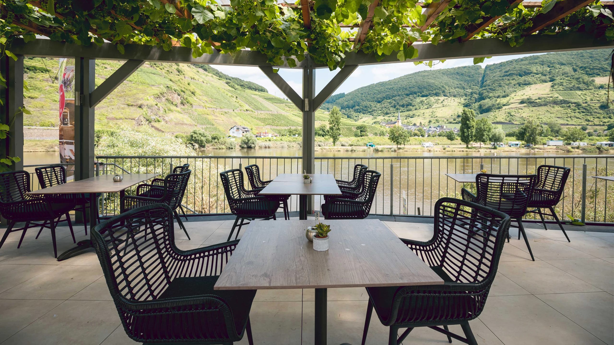 Terrasse unter Weinlaub mit Blick über die Mosel auf die Weinberge
