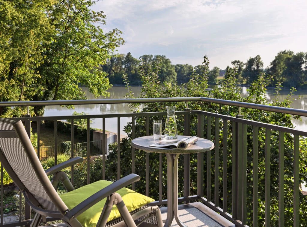 Balkon mit Liegestuhl und kleinem Tisch, Blick über den Fluss ins Grüne