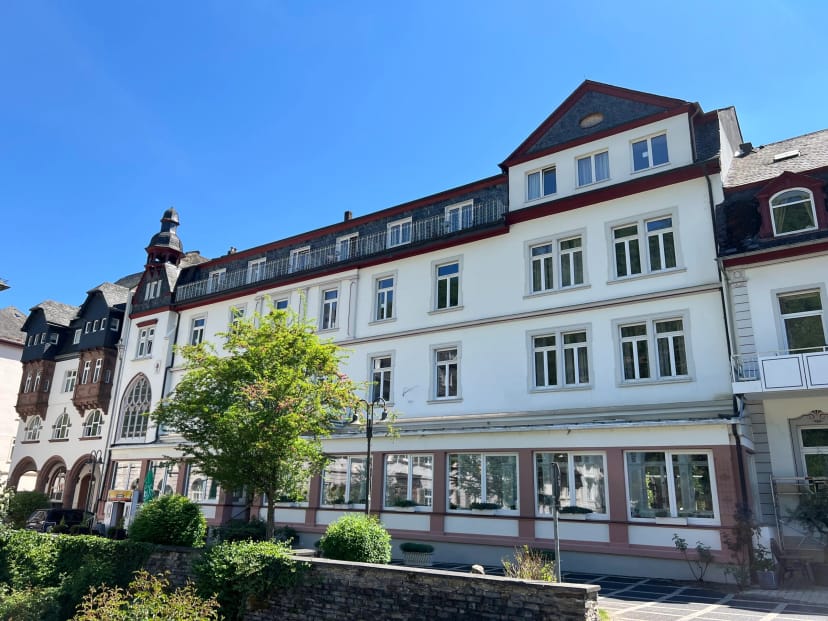 Vorderansicht des historischen Hotelgebäudes mit heller Fassade bei blauem Himmel