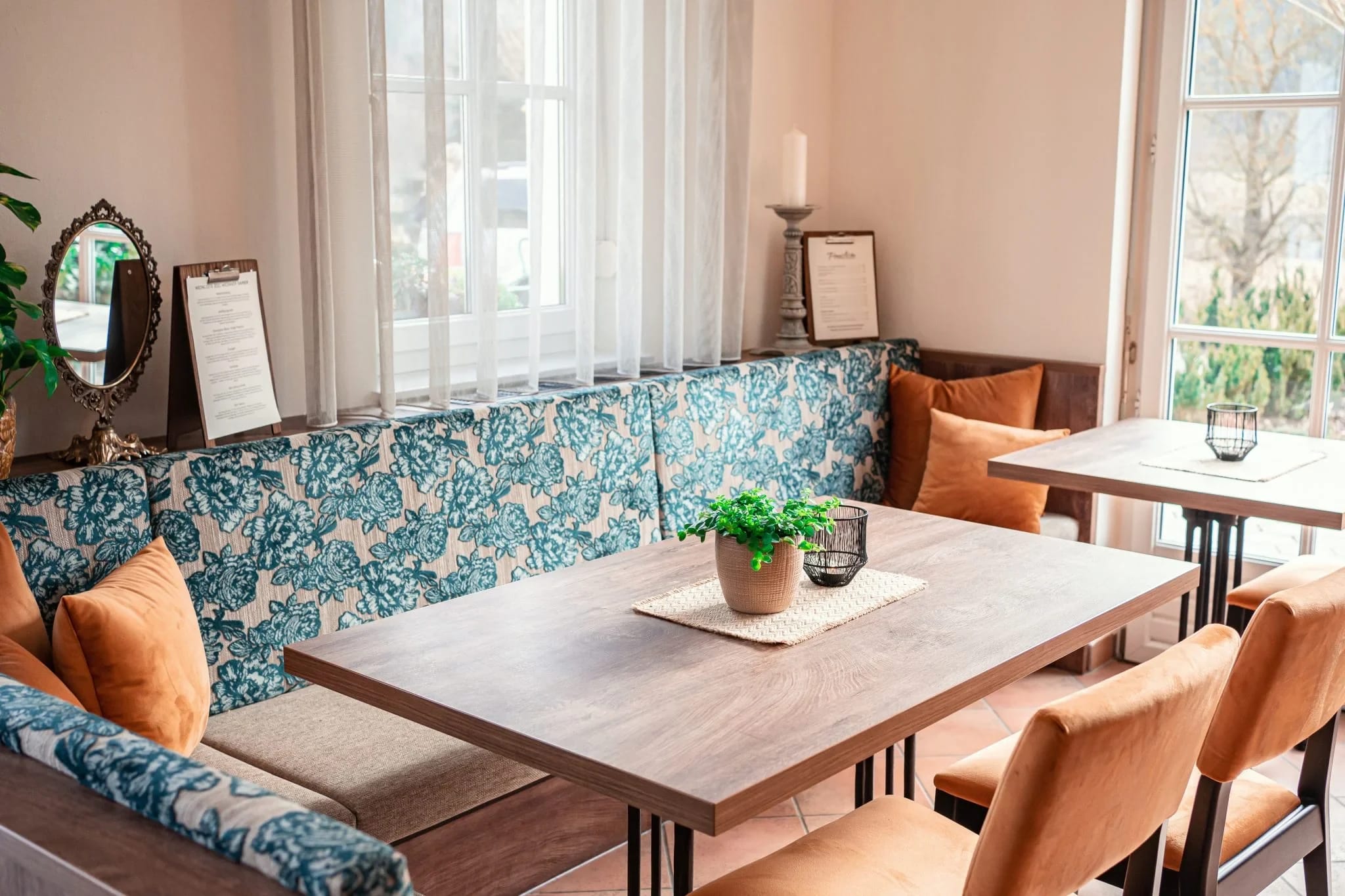 Frühstücksraum mit gemusterter Sitzbank, Holztischen und Polsterstühlen
