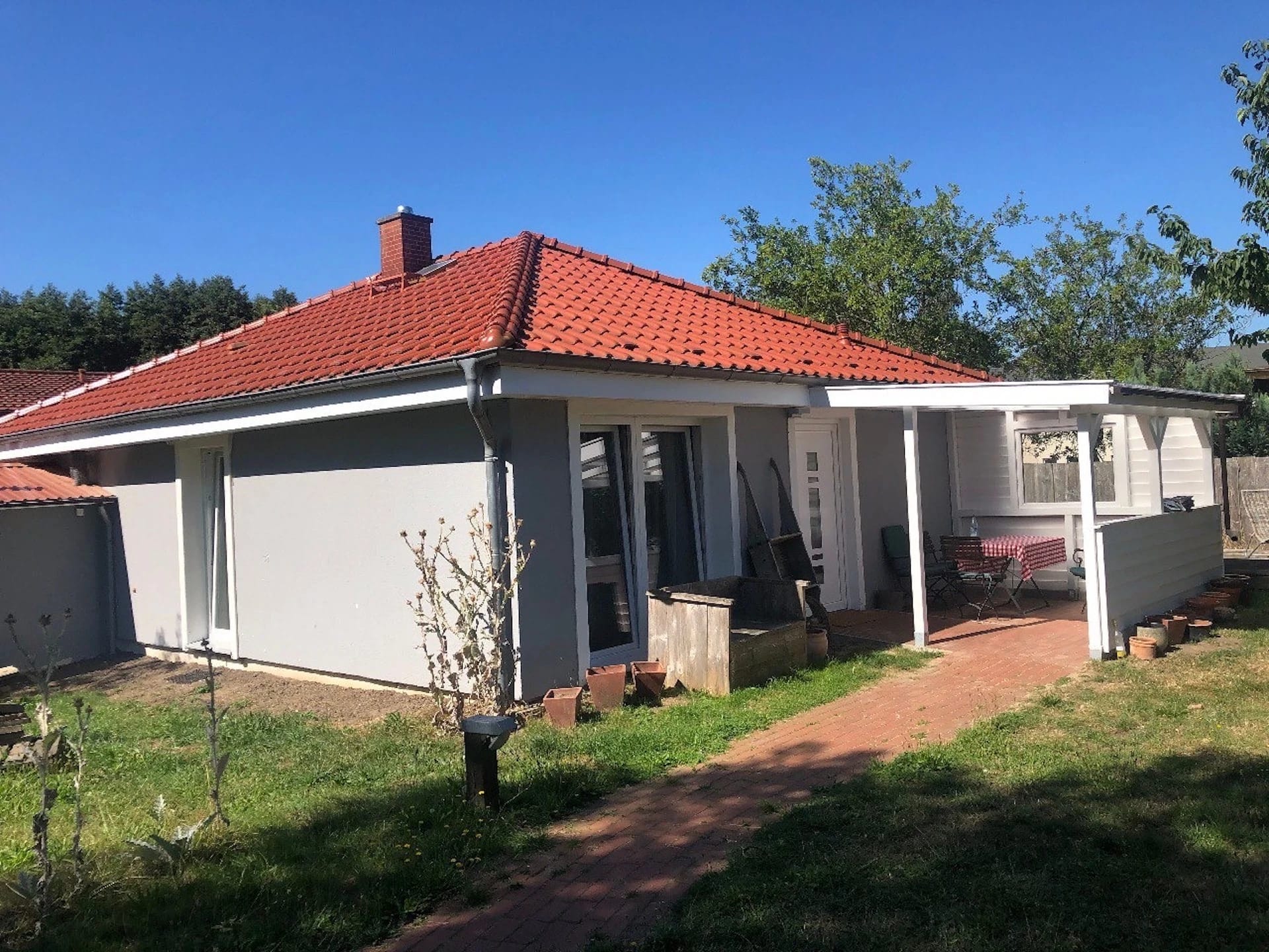Ferienhaus mit rotem Ziegeldach, überdachter Terrasse und Garten