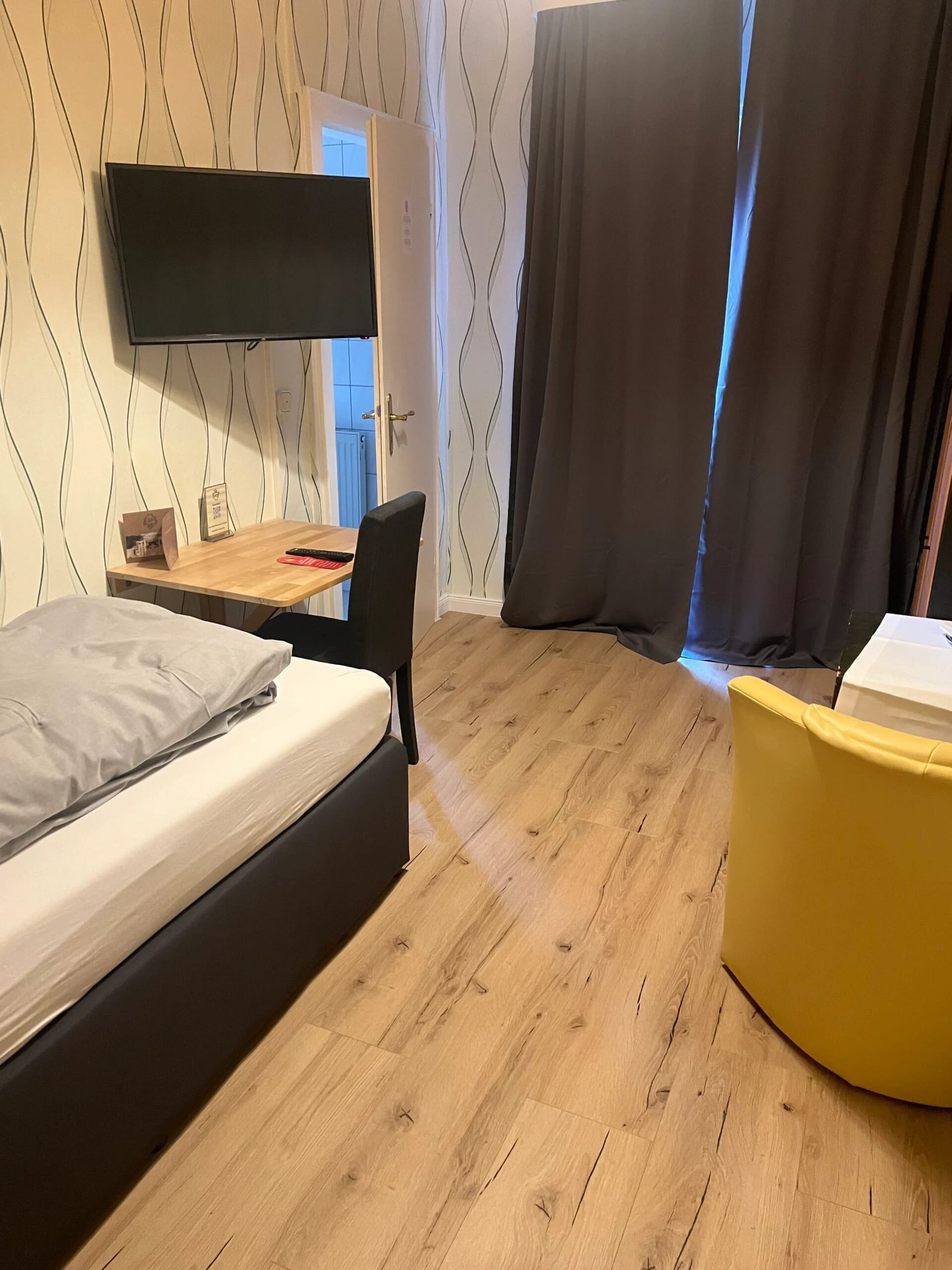Einzelzimmer mit Bett, Schreibtisch und Sessel