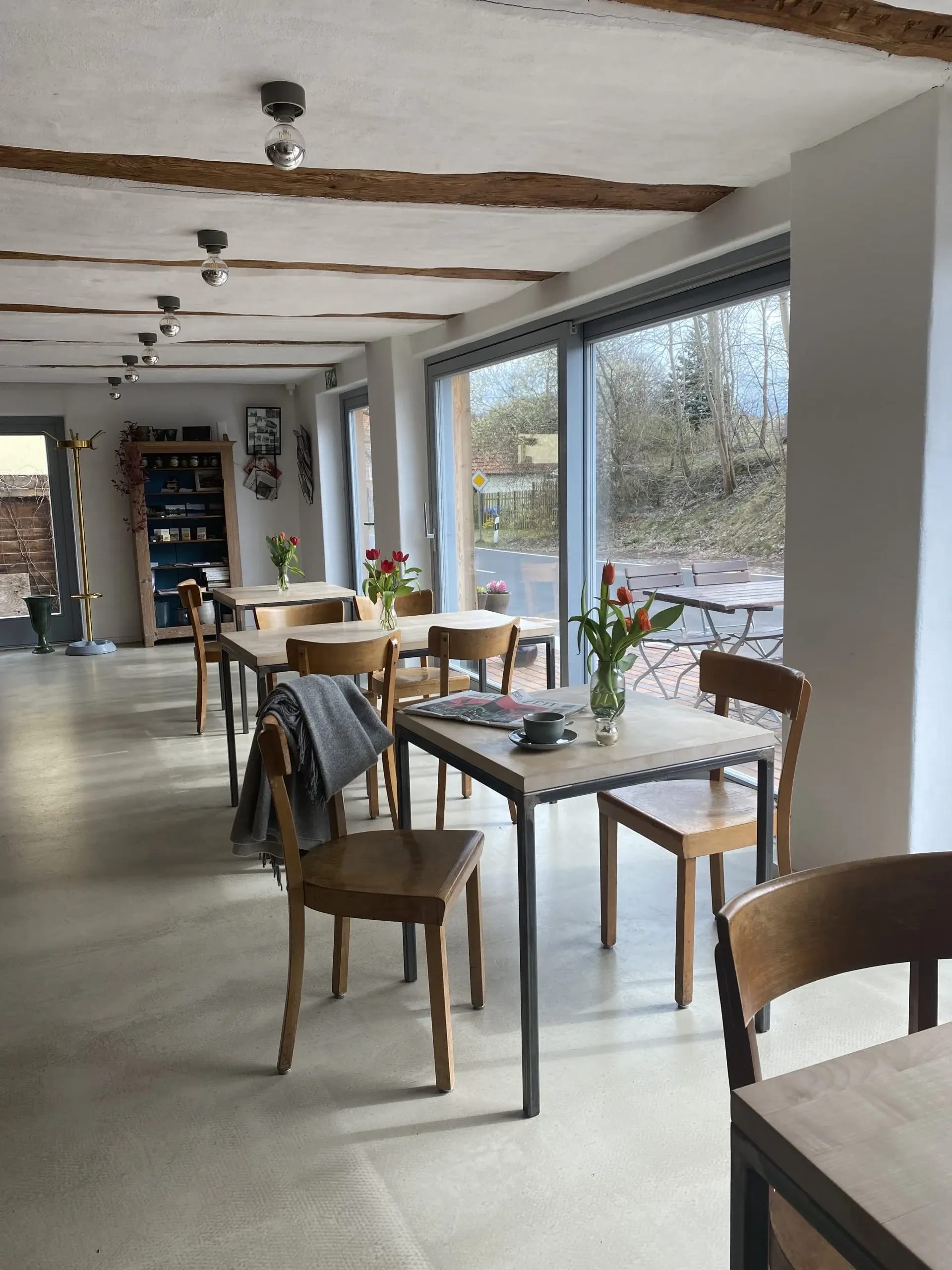 Gastraum mit Holztischen und Stühlen sowie großen Fenstern zur Terrasse