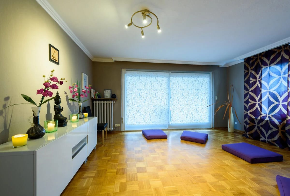 Yogaraum mit Parkettboden, Sitzkissen und Orchideen auf einem Sideboard
