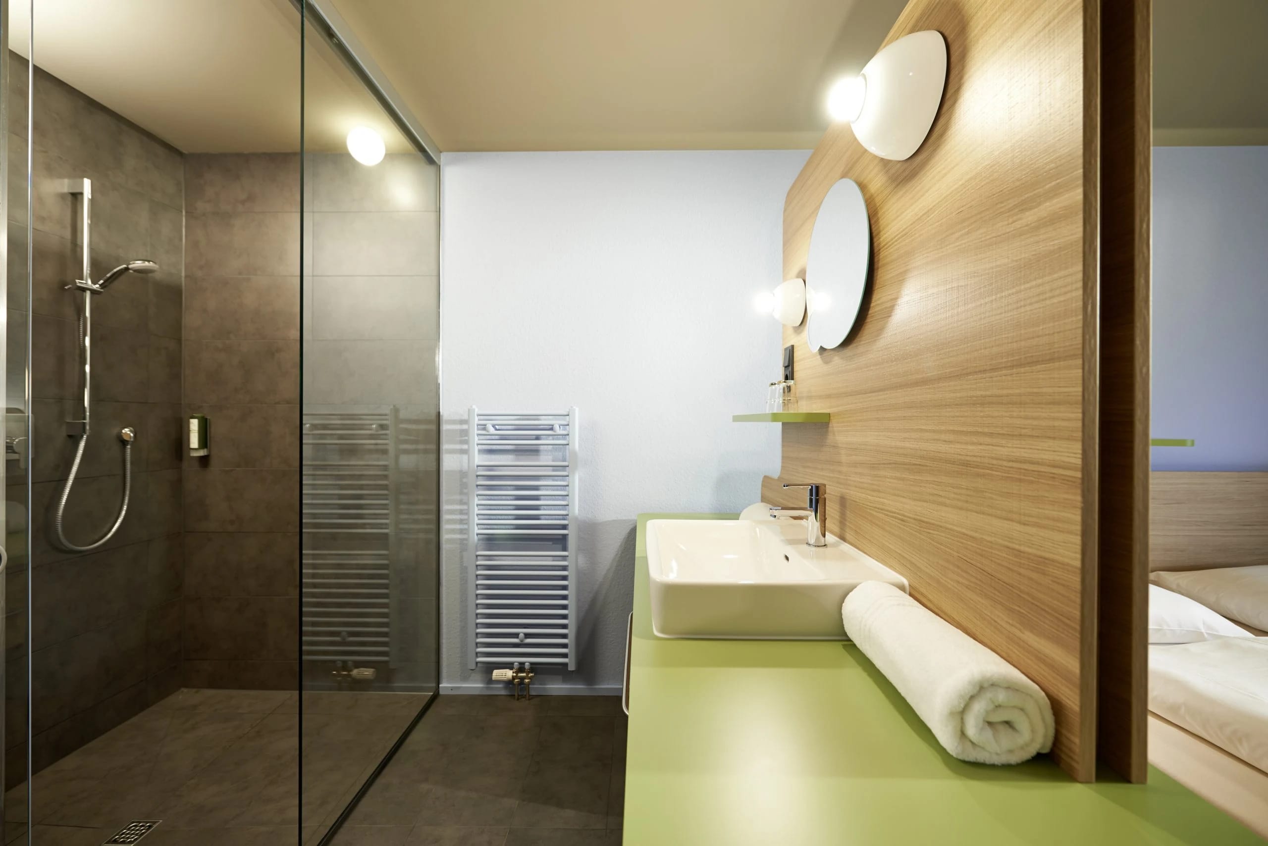 Modernes Bad mit ebenerdiger Dusche und Waschbecken vor Holzwand