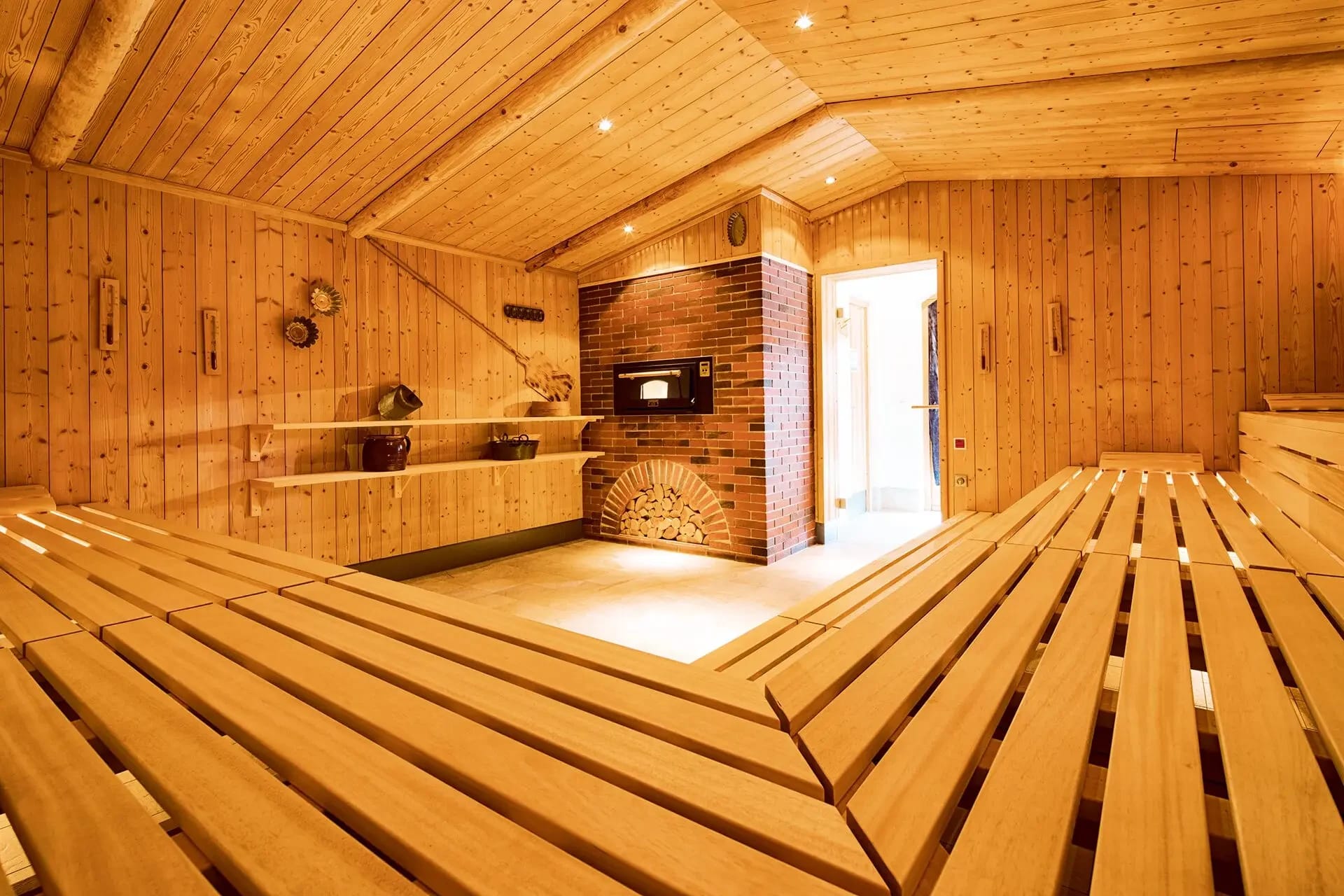 Große Saunakabine aus Holz mit Backsteinofen und breiten Sitzstufen