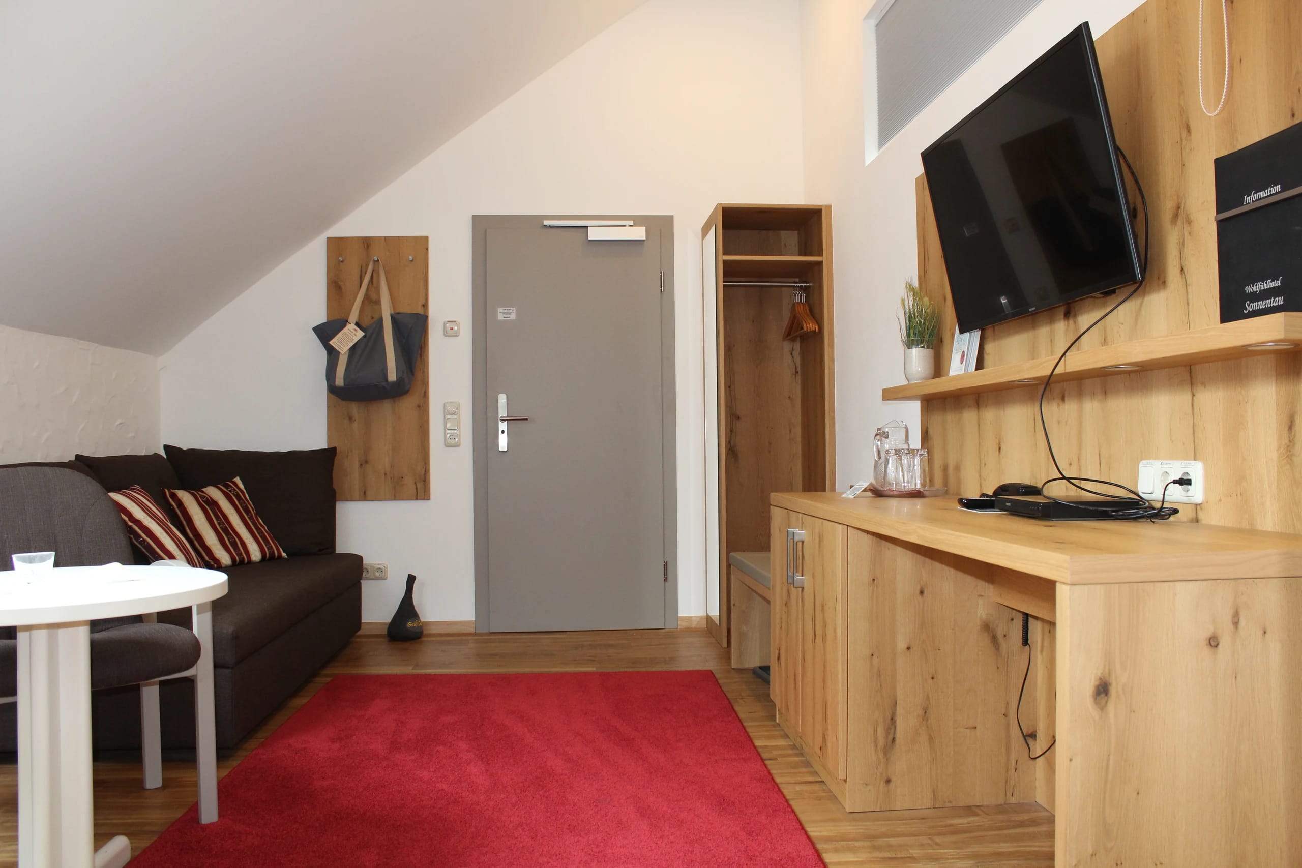 Apartment mit Sofa, Holzsideboard und Wandfernseher im Eingangsbereich