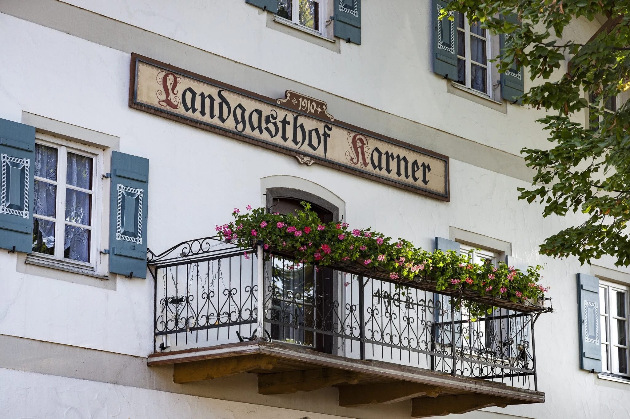 Fassade des Landgasthofs Karner mit verziertem Balkon und blauen Fensterläden