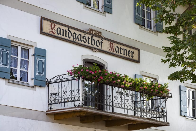 Fassade des Landgasthofs Karner mit verziertem Balkon und blauen Fensterläden
