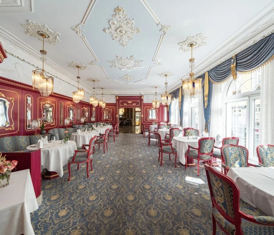 Restaurantraum mit grünen Wänden, rotem Musterteppich und Kronleuchtern