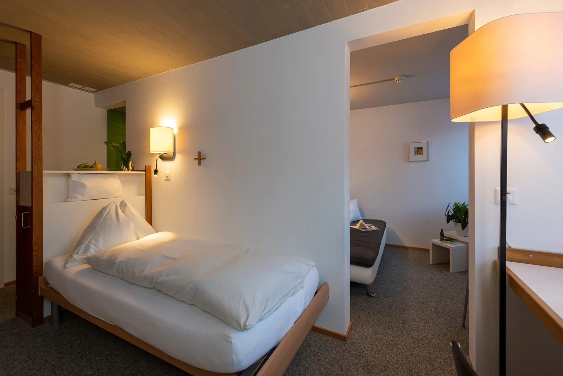 Gästezimmer mit Bett, Stehlampe und angrenzender Sitzecke