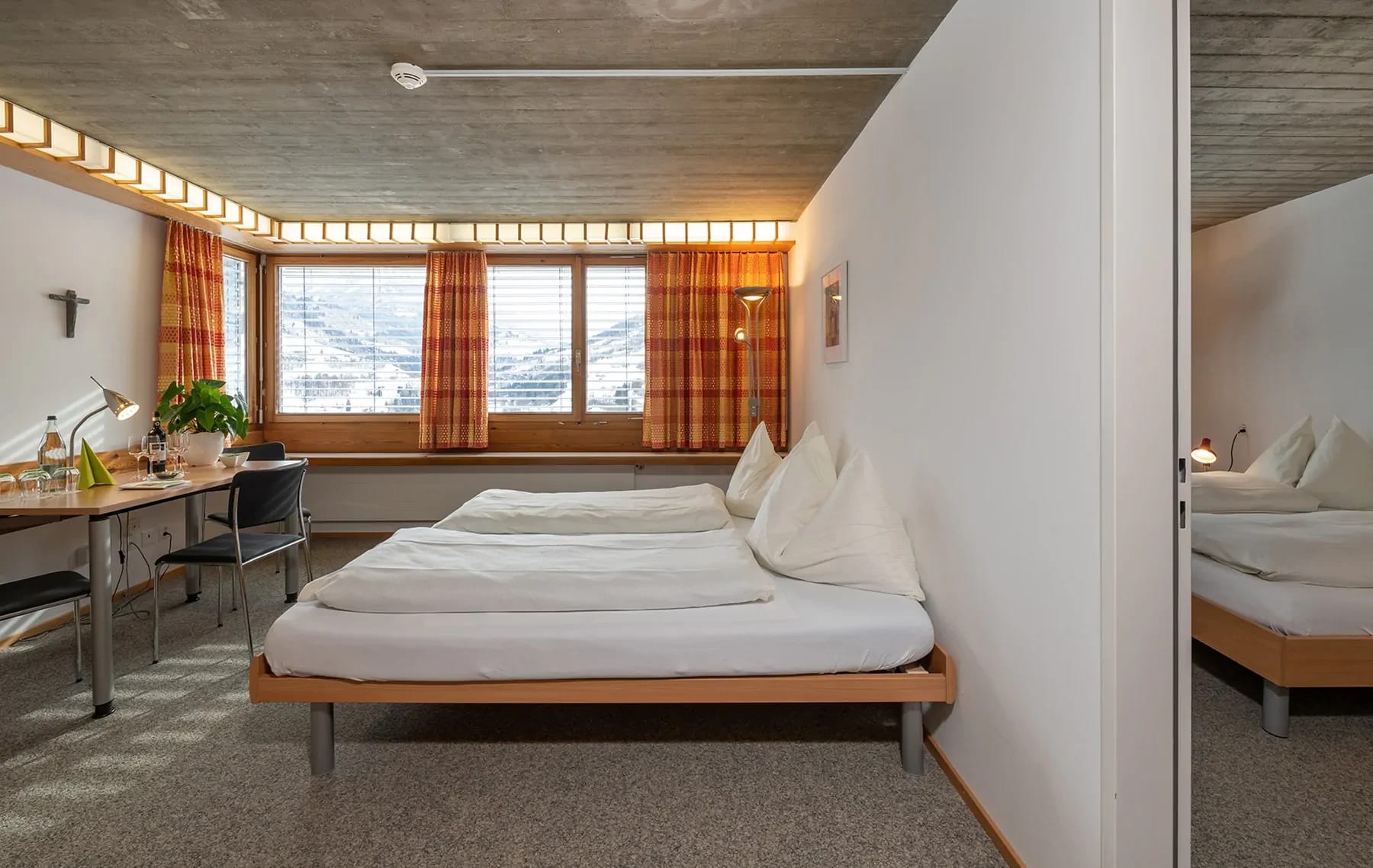 Zimmer mit zusammengestellten Betten, Schreibtisch am Fenster und Blick auf die Berge