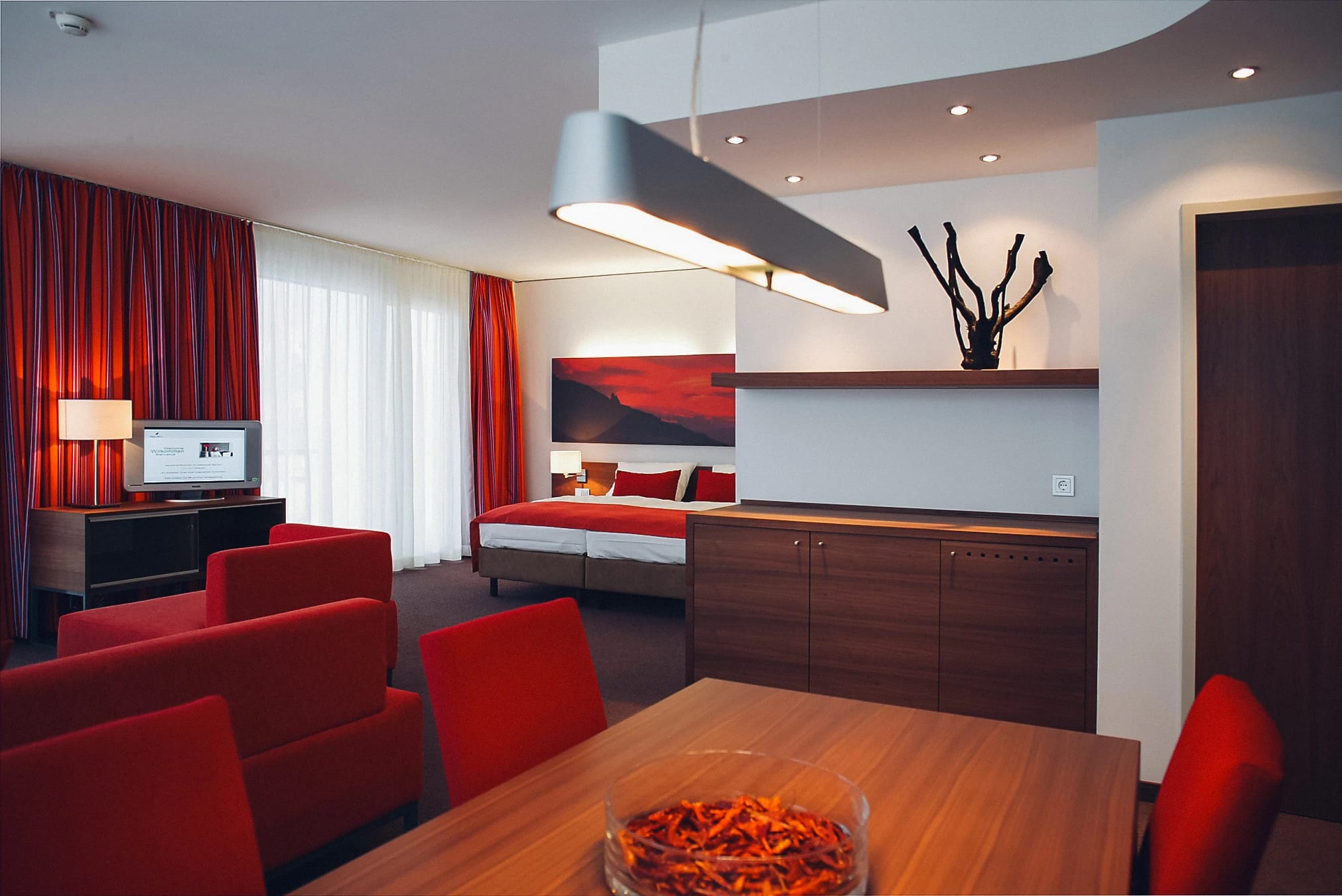 Suite mit Wohnbereich, Esstisch mit Sesseln und Schlafbereich im Hintergrund