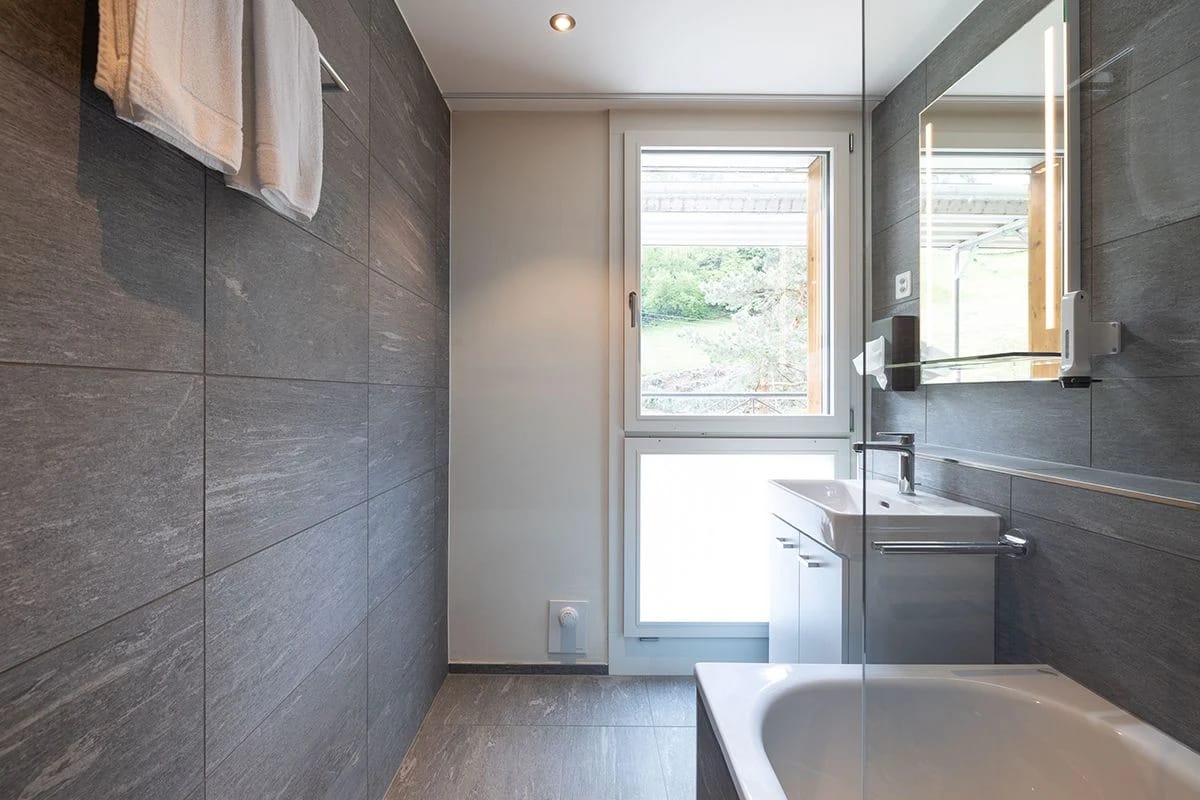 Badezimmer mit Badewanne, Waschtisch und Fenster