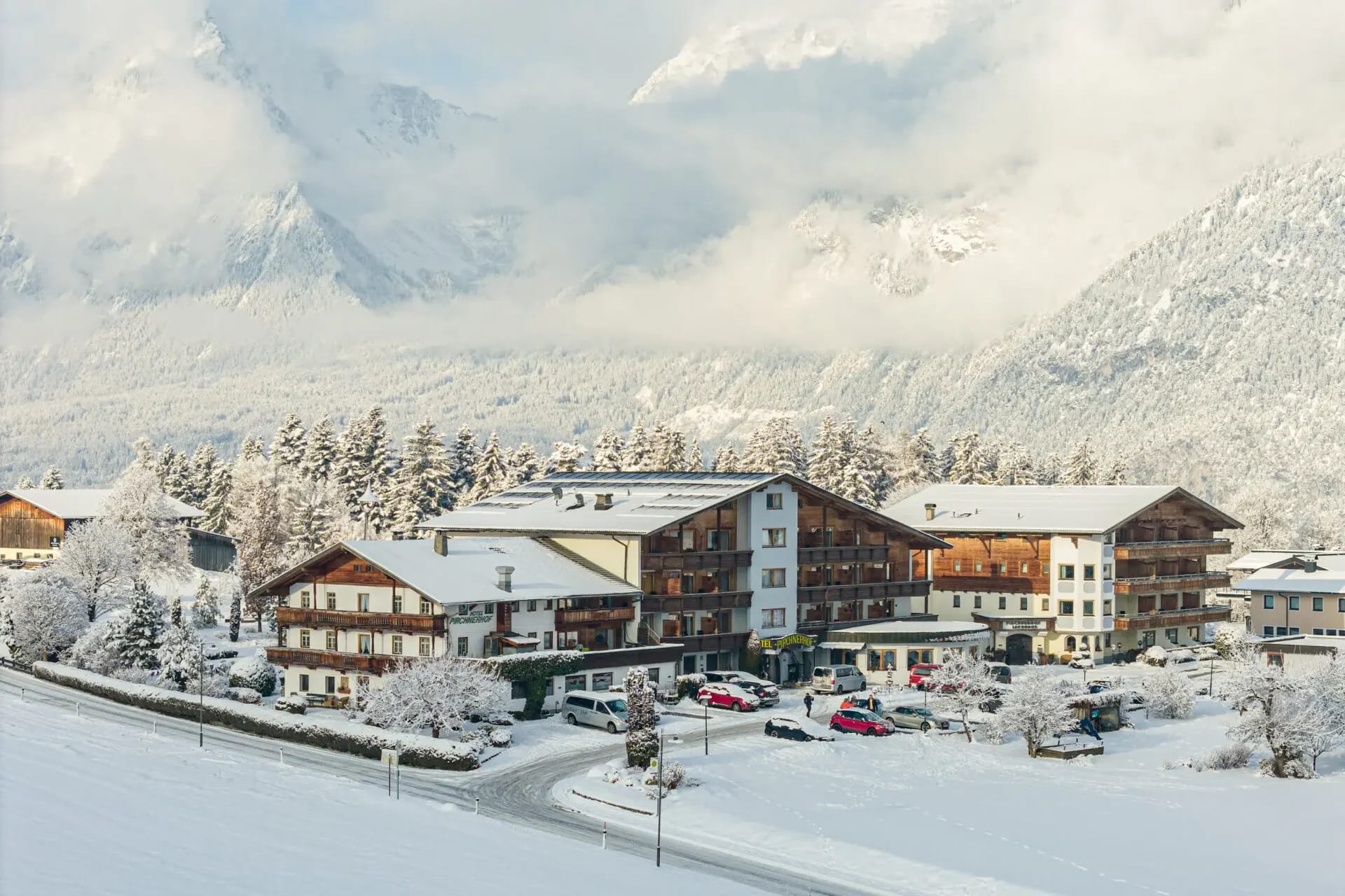 Das Hotel Pirchnerhof im Winter in einer verschneiten Landschaft mit Tiroler Bergen im Hintergrund
