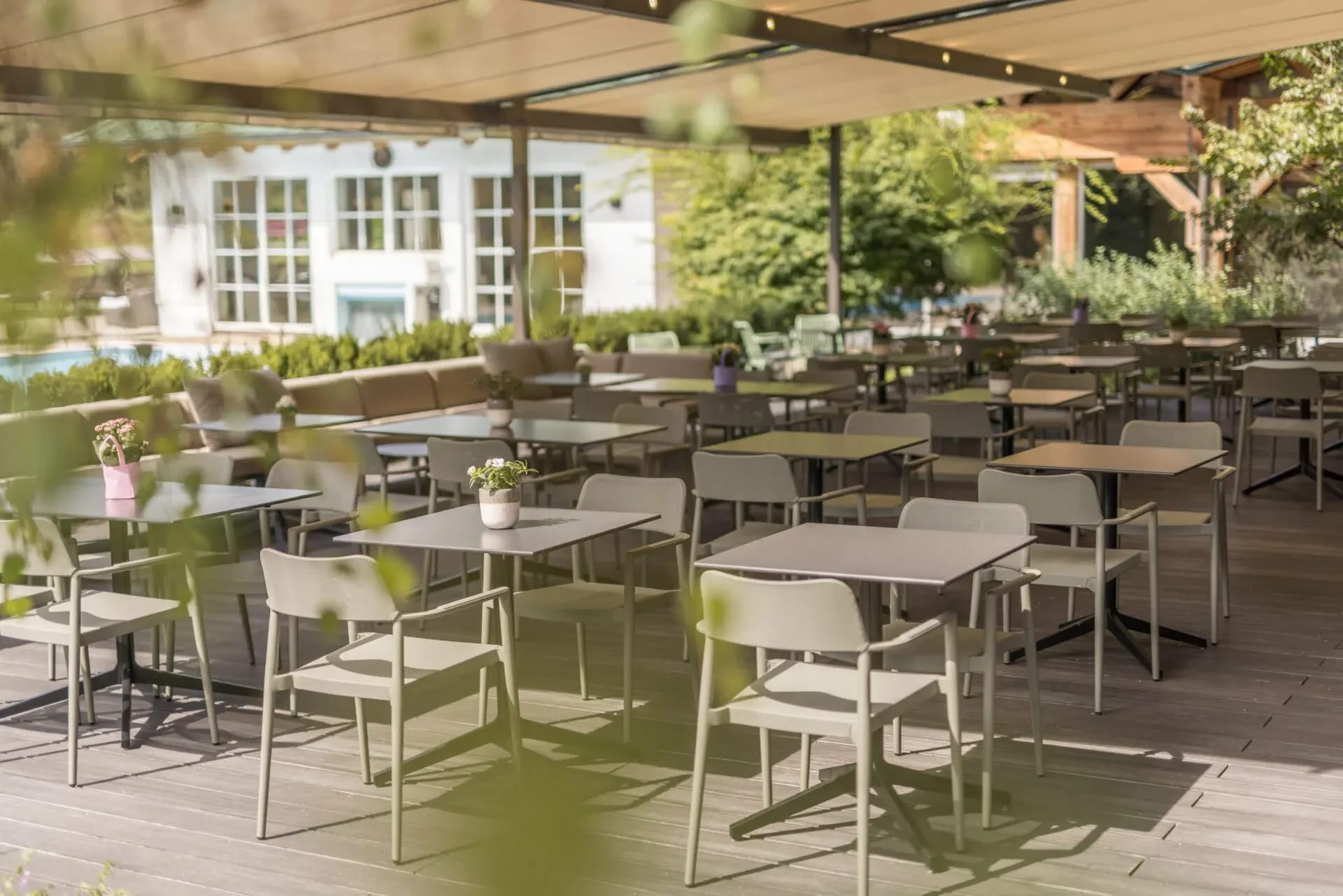 Sonnige Außenterrasse des Hotel Pirchnerhof mit Tischen und Stühlen unter einem Sonnendach