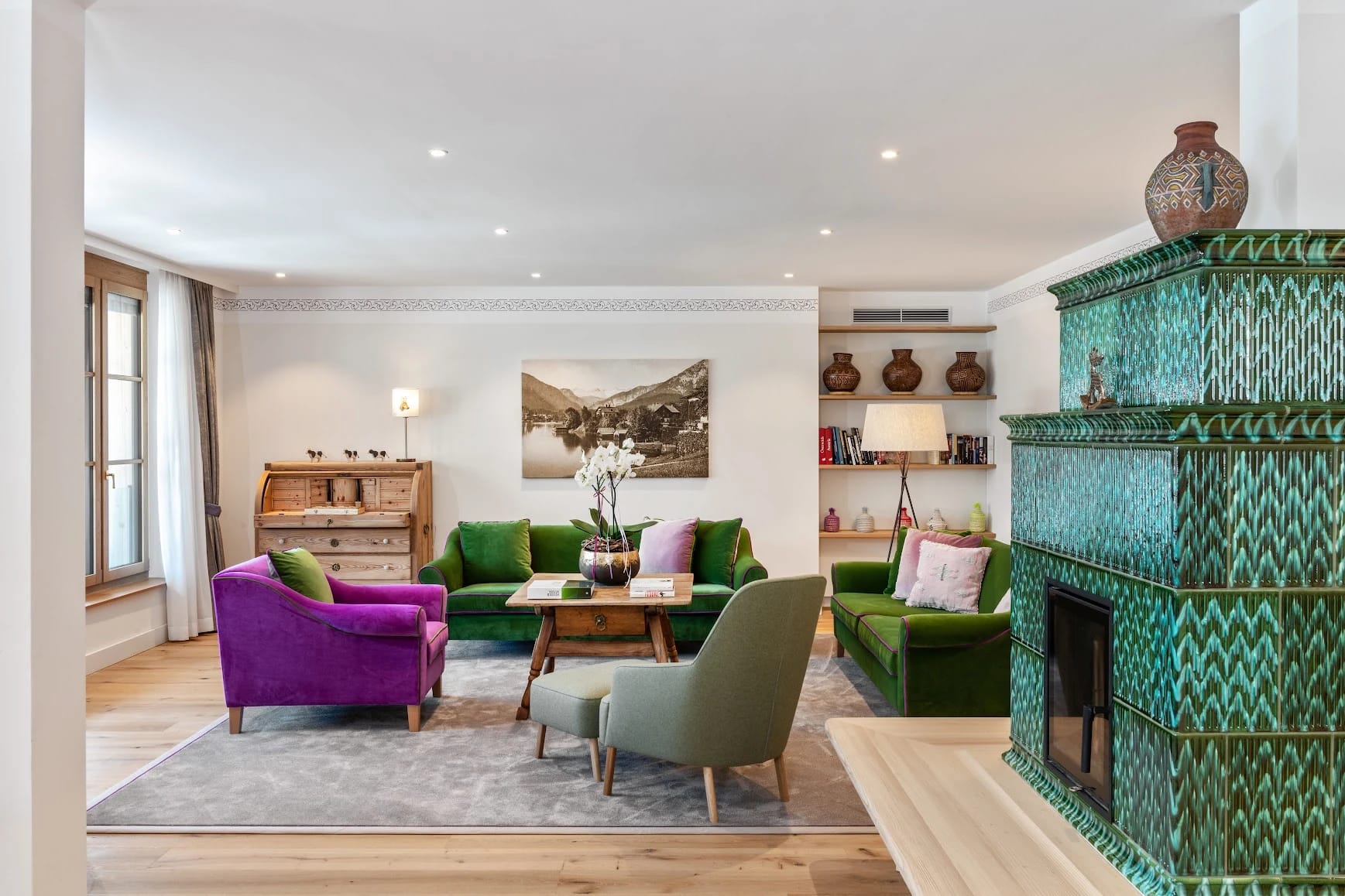 Wohnraum mit grünem Kachelofen, grünem Sofa, Sesseln und Sekretär