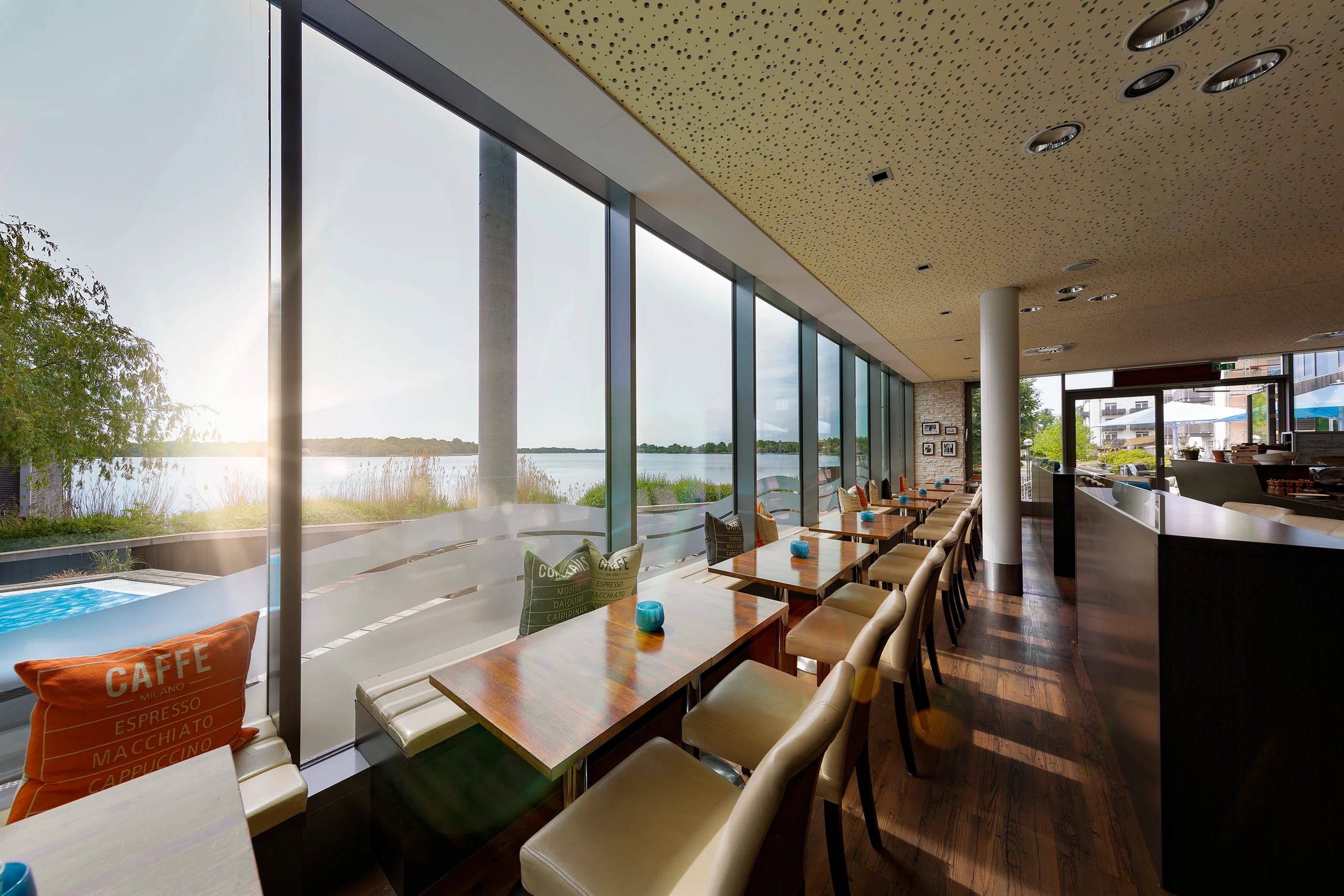 Bistro mit langer Fensterfront zum Ruppiner See, davor Sitzplätze an Holztischen
